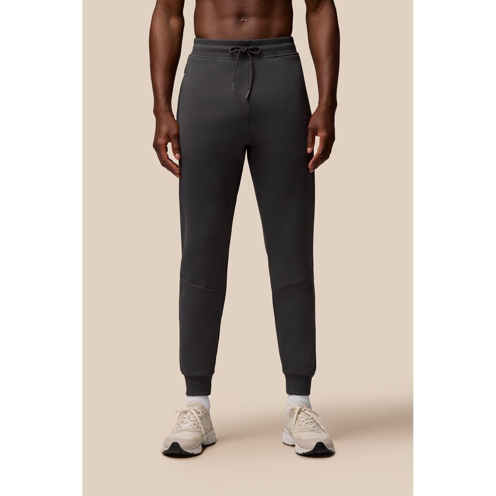 Men's grey joggers made of polyester, featuring a drawstring waist, tapered legs, and ribbed cuffs, styled with a sleek, modern look.