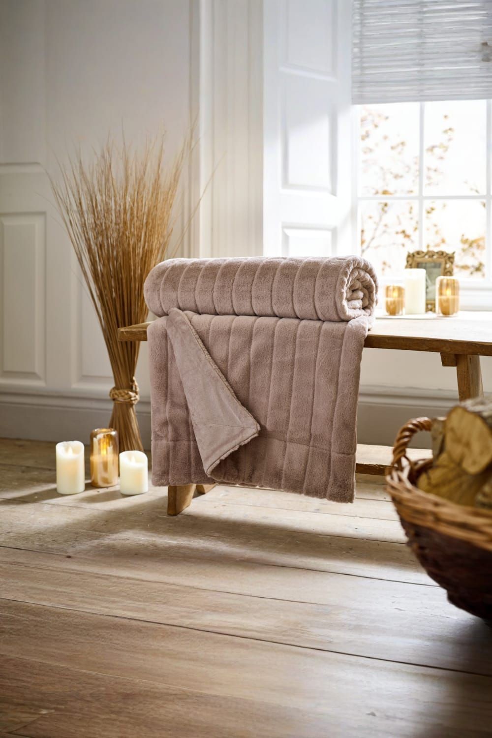 Soft fawn-colored quilted throw blanket, measuring 150x200cm, made from plush material, elegantly draped over a wooden bench with candles and decorative elements in the background.