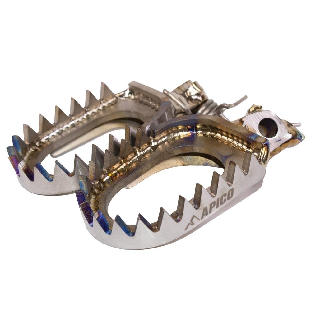Open design titanium foot pegs by Apico, featuring a shiny metallic finish, serrated edges for grip, and a lightweight construction, suitable for various Yamaha models from 1998 to 2025.