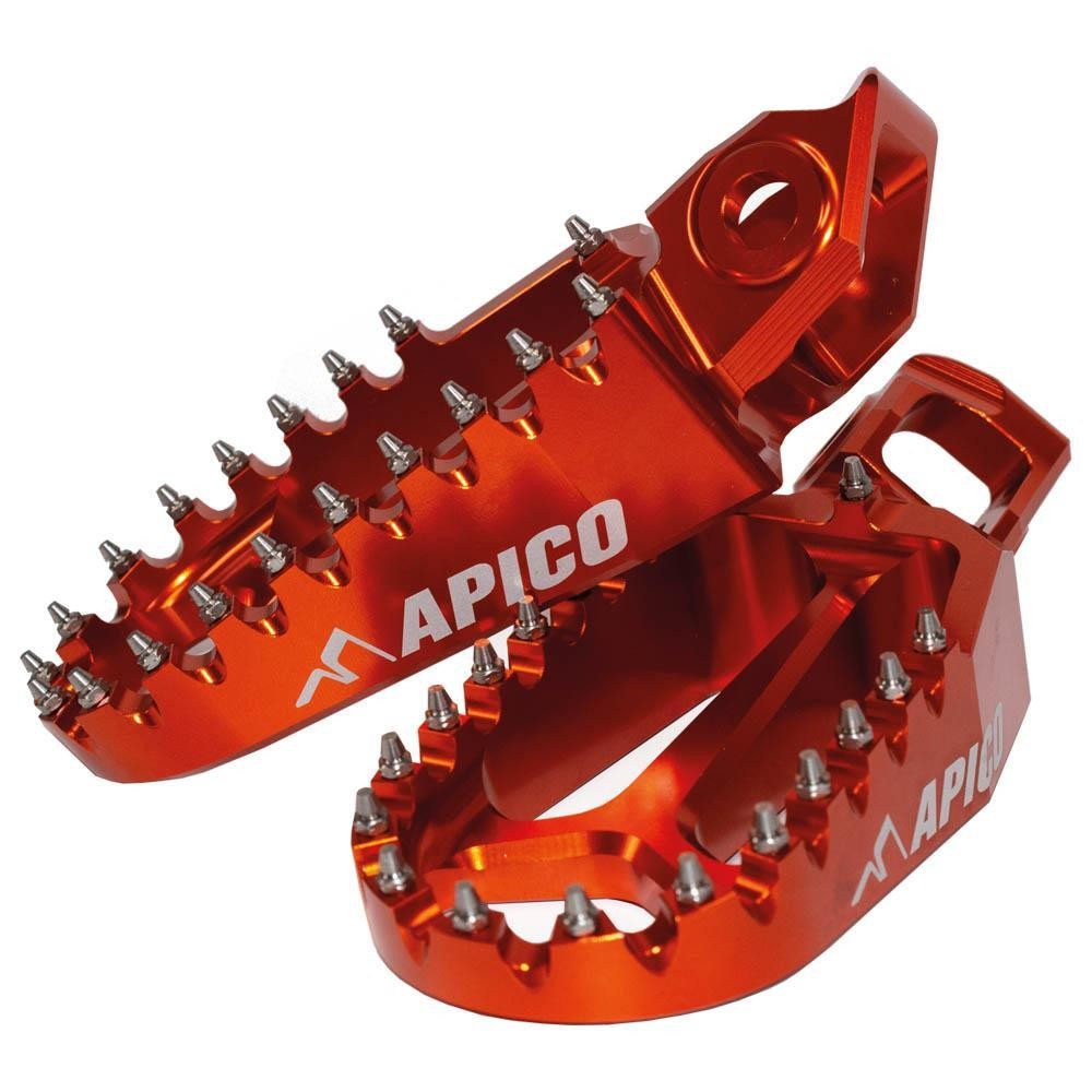 Bright orange aluminum foot pegs with a rugged design, featuring multiple metal spikes for grip, and the "APICO" logo prominently displayed on the side.