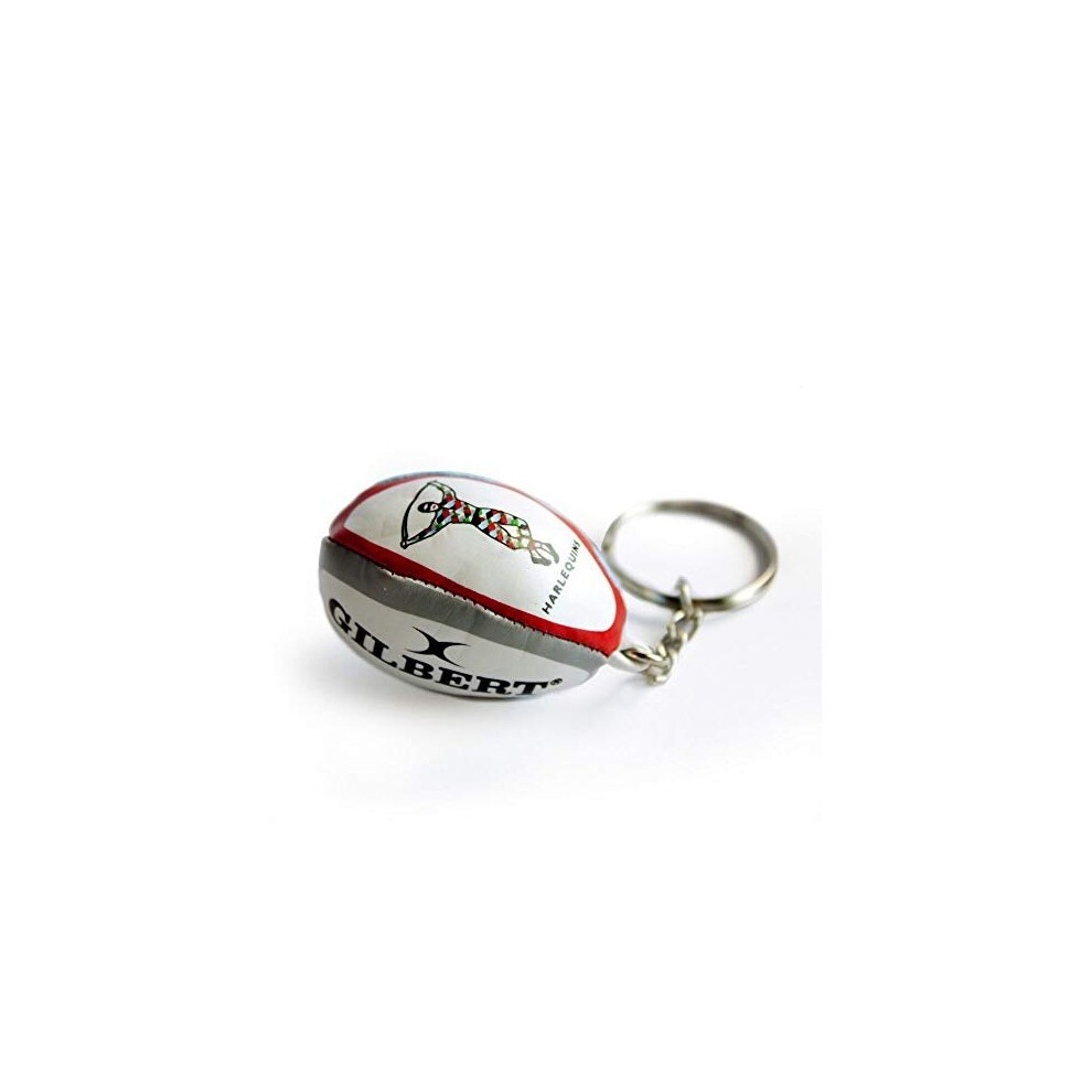 A miniature rugby ball keyring in white, red, and green, featuring the Harlequins logo and "Gilbert" branding, made of soft material with a metal keyring attachment.