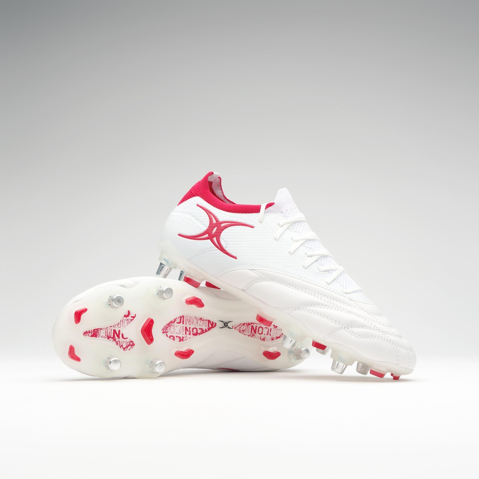 Black junior rugby boots with six studs, featuring a sleek design, white upper material, and vibrant pink accents on the heel and logo.