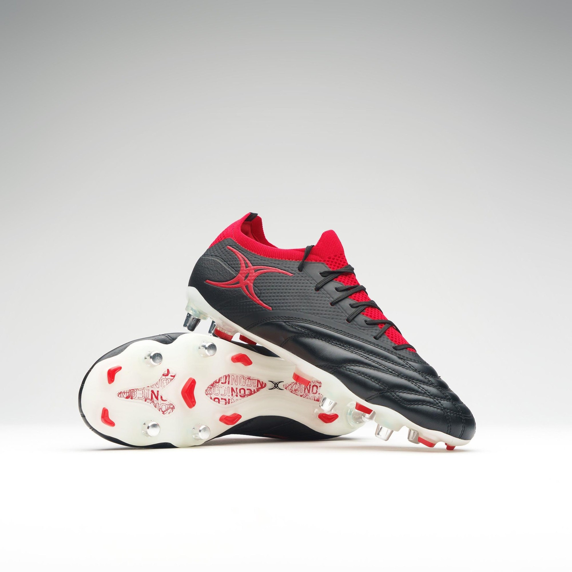 Black rugby boots with red accents, featuring a textured upper, six stud configuration, and a sleek design for enhanced performance on the field.