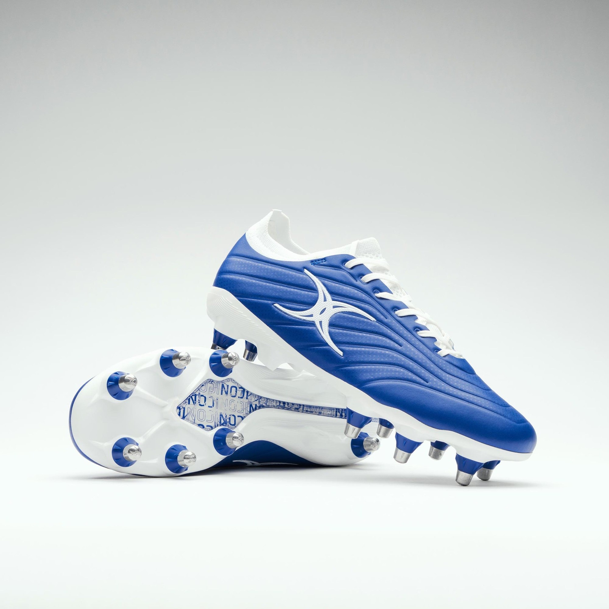 Blue synthetic rugby boots with white accents, featuring eight studs on the sole for traction, and a prominent Gilbert logo on the side.