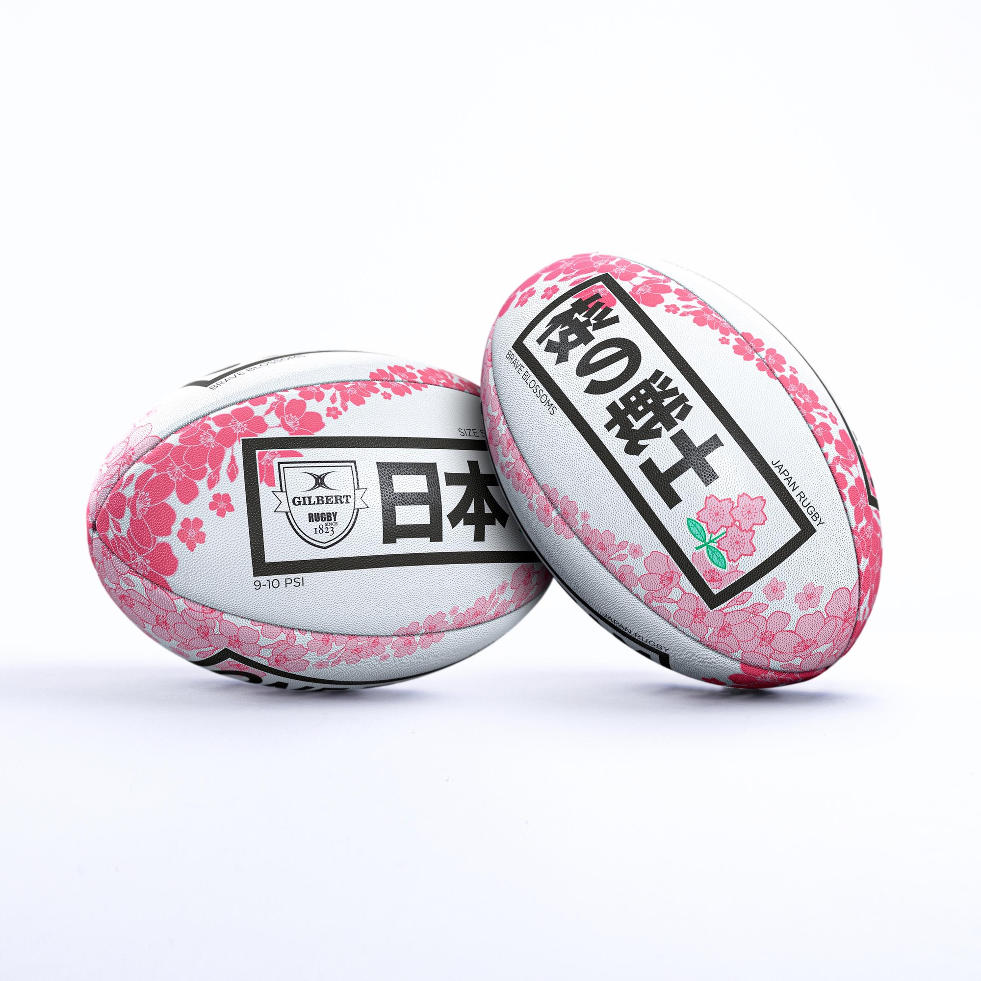 White rugby ball featuring pink cherry blossom designs and Japanese text, with a textured surface and a recommended pressure of 9-10 PSI, representing Japan's national colors.