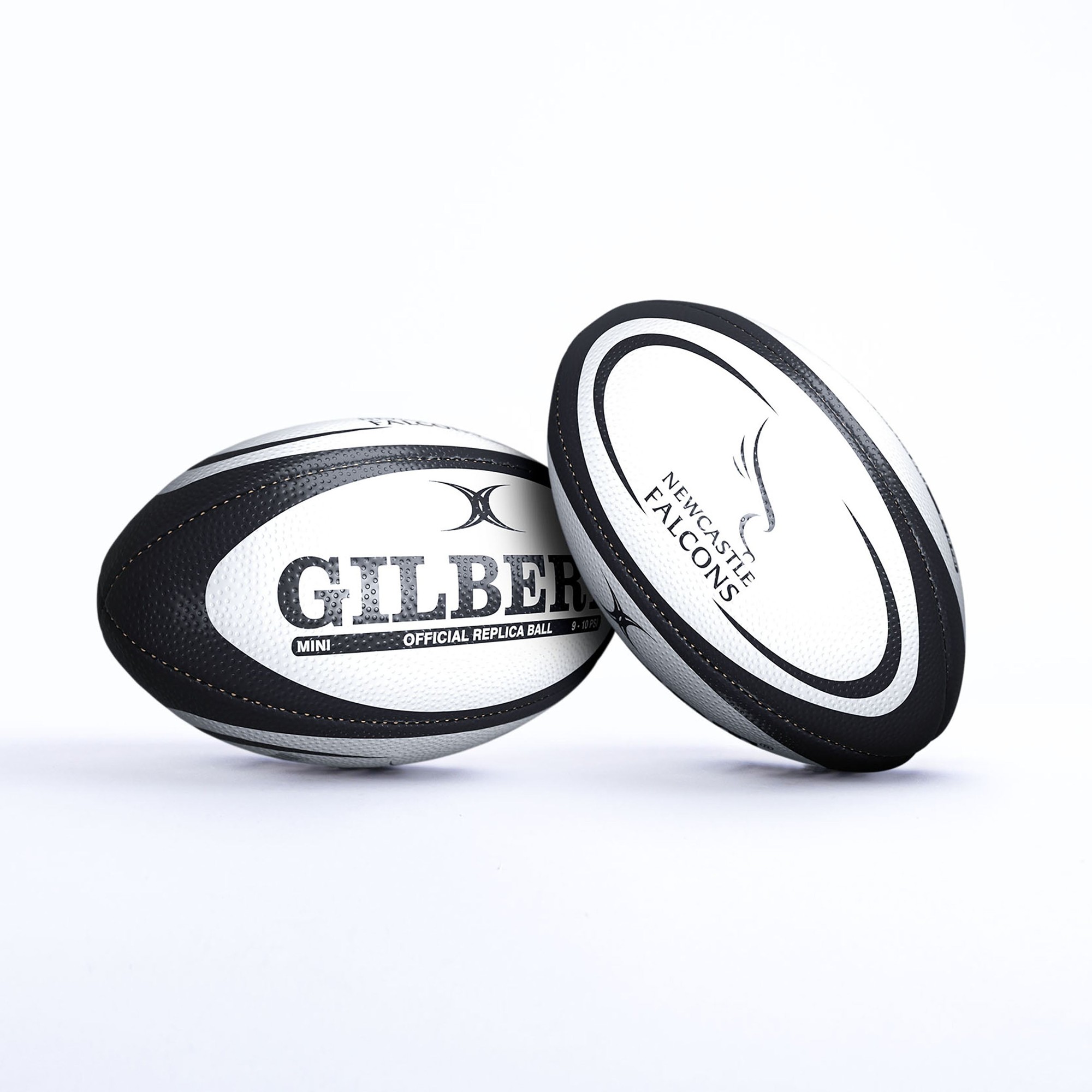 White rugby ball with black accents, featuring "GILBERT" and "NEWCASTLE FALCONS" logos, made from textured synthetic material, designed for replica use.