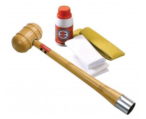 Gray-Nicolls Bat Conditioning Kit featuring a wooden mallet, red and white conditioning oil, a yellow grip, and two white cloths, all in assorted colors.