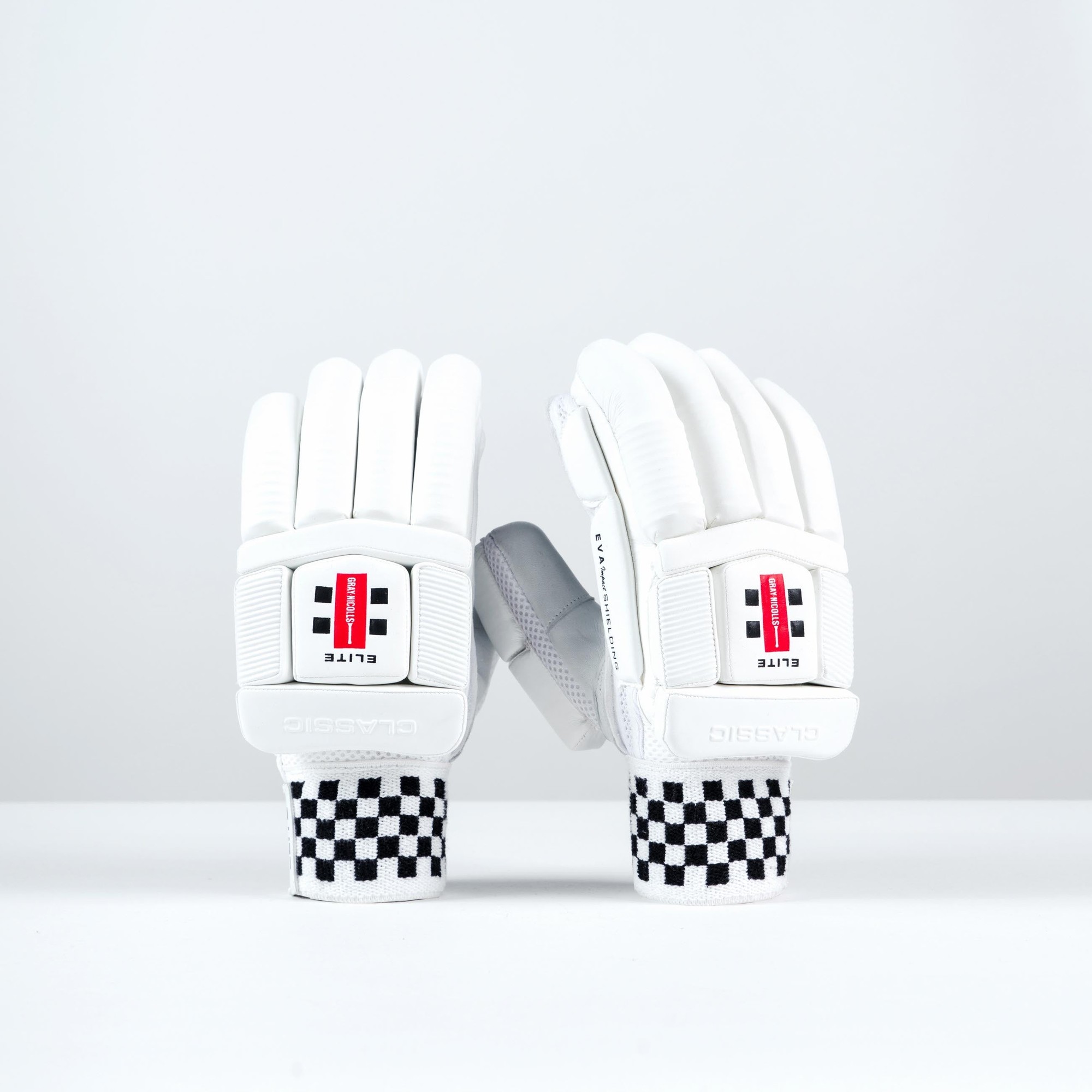 White Gray-Nicolls Classic Elite batting gloves featuring padded protection, a textured grip, and a black and white checkered wristband for added style.