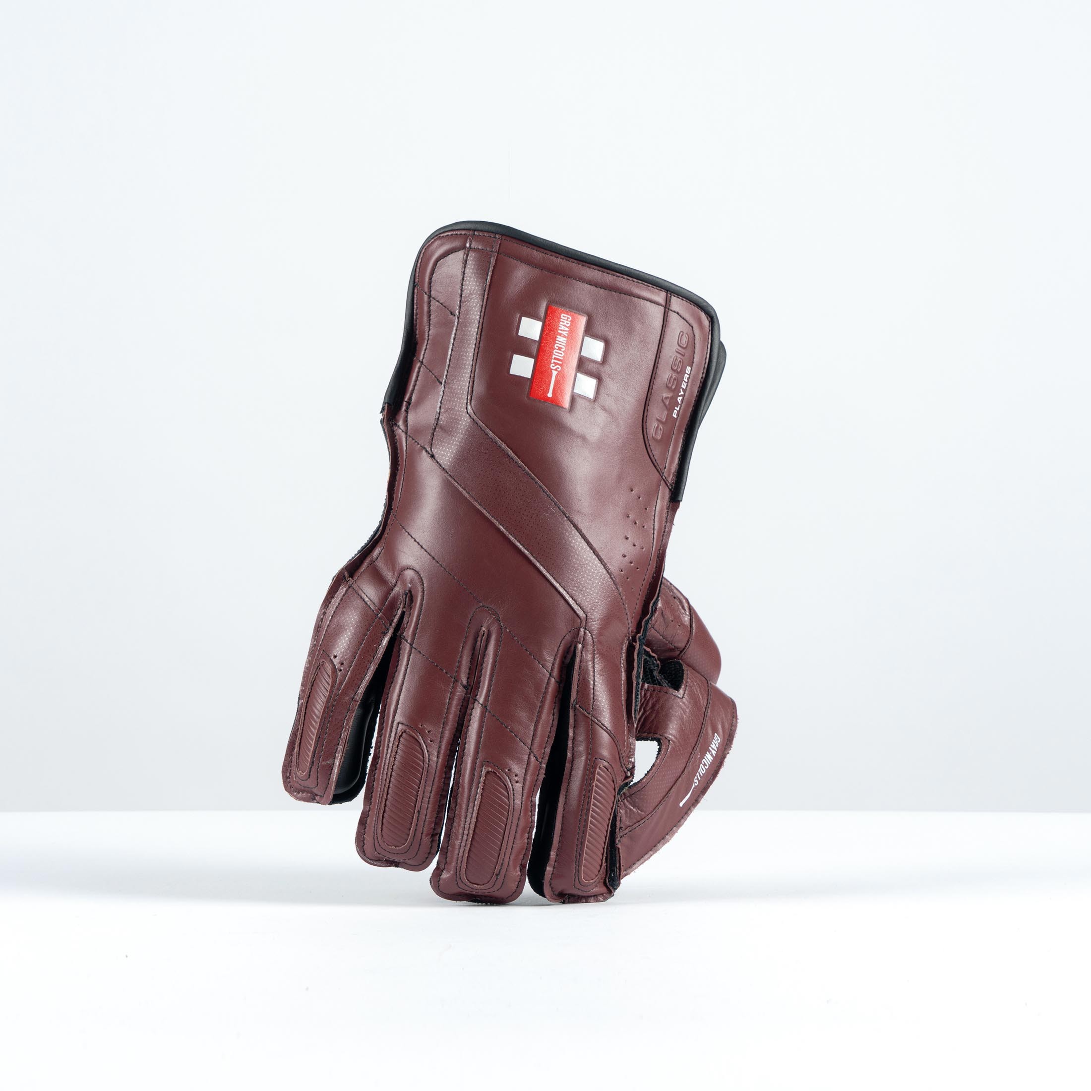 Gray-Nicolls Classic Players Edition adult wicketkeeping glove in maroon and white, featuring a leather finish and padded fingers for enhanced protection and grip.