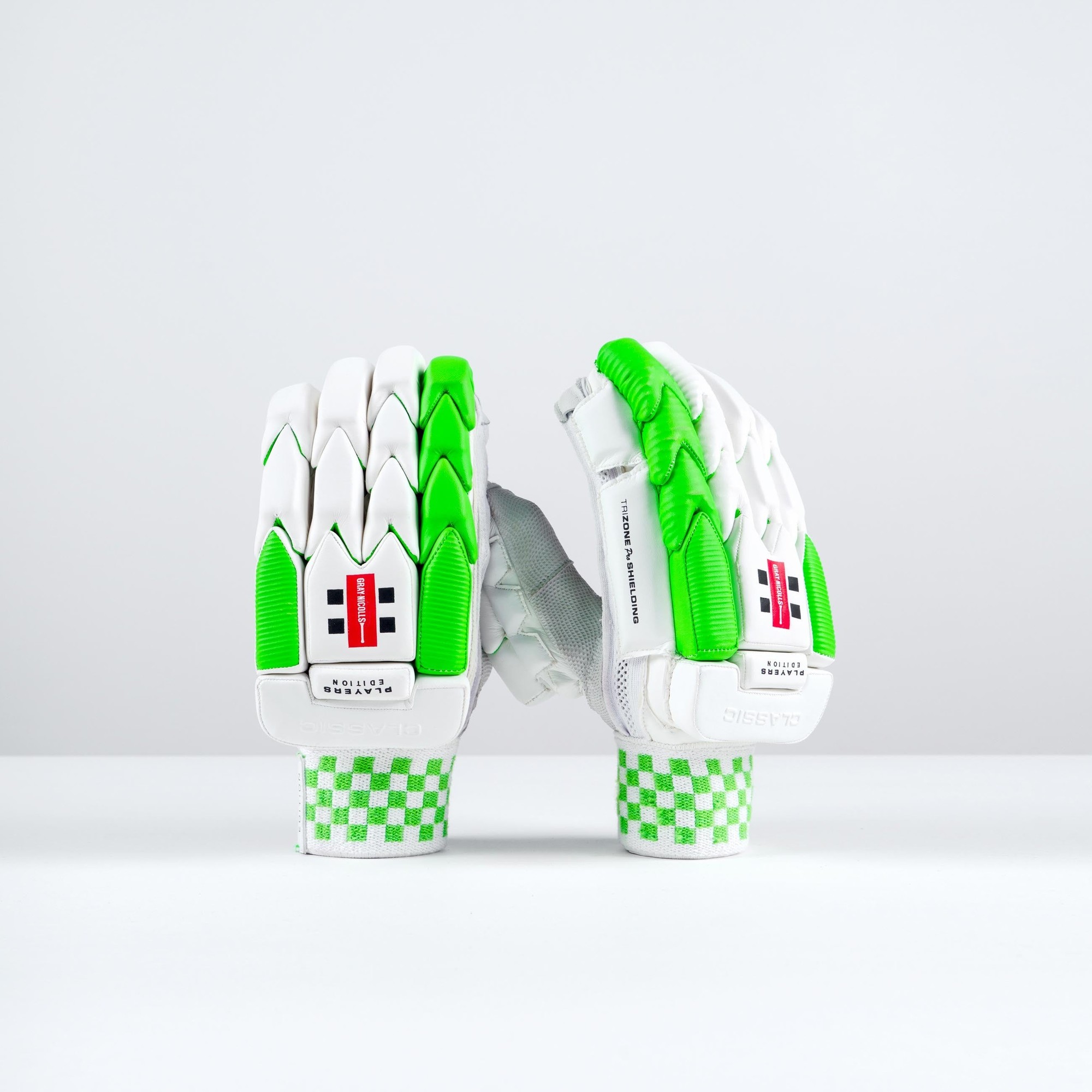 Gray-Nicolls Classic Players Edition batting gloves in white and green, featuring padded fingers, a textured grip, and a checkered wristband for enhanced comfort and protection.