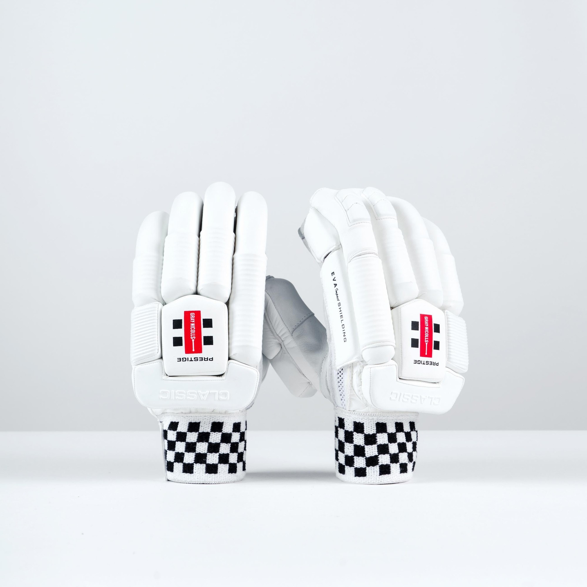 White Gray-Nicolls Classic Prestige batting gloves featuring padded protection, a textured grip, and a distinctive black and white checkered wristband.