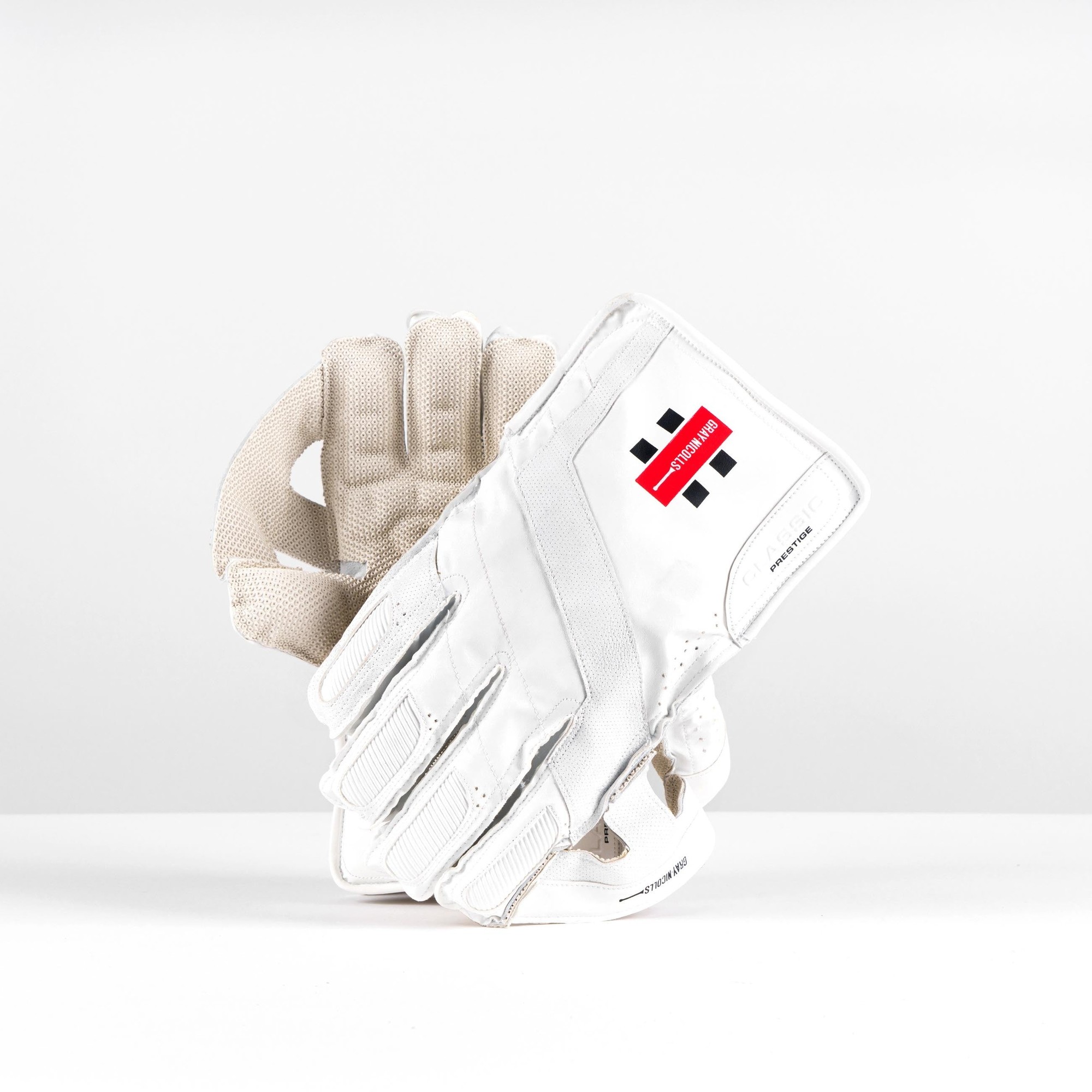 White Gray-Nicolls Classic Prestige wicketkeeping glove featuring a textured palm, reinforced fingers, and a distinctive red and black logo.
