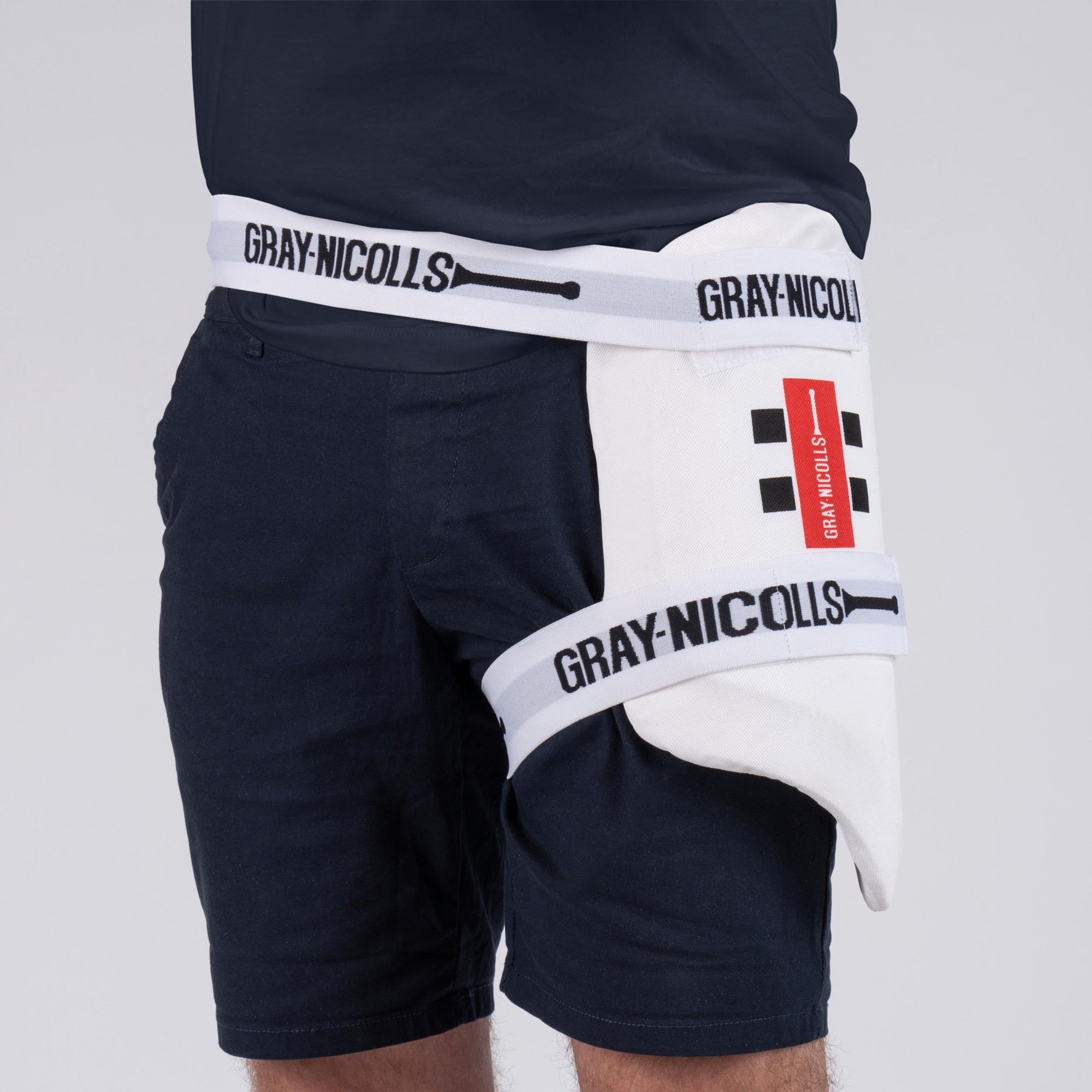 White Gray-Nicolls Club Collection cricket thigh pads featuring a sleek design, adjustable straps, and a comfortable fit, worn on a model's leg against a neutral background.