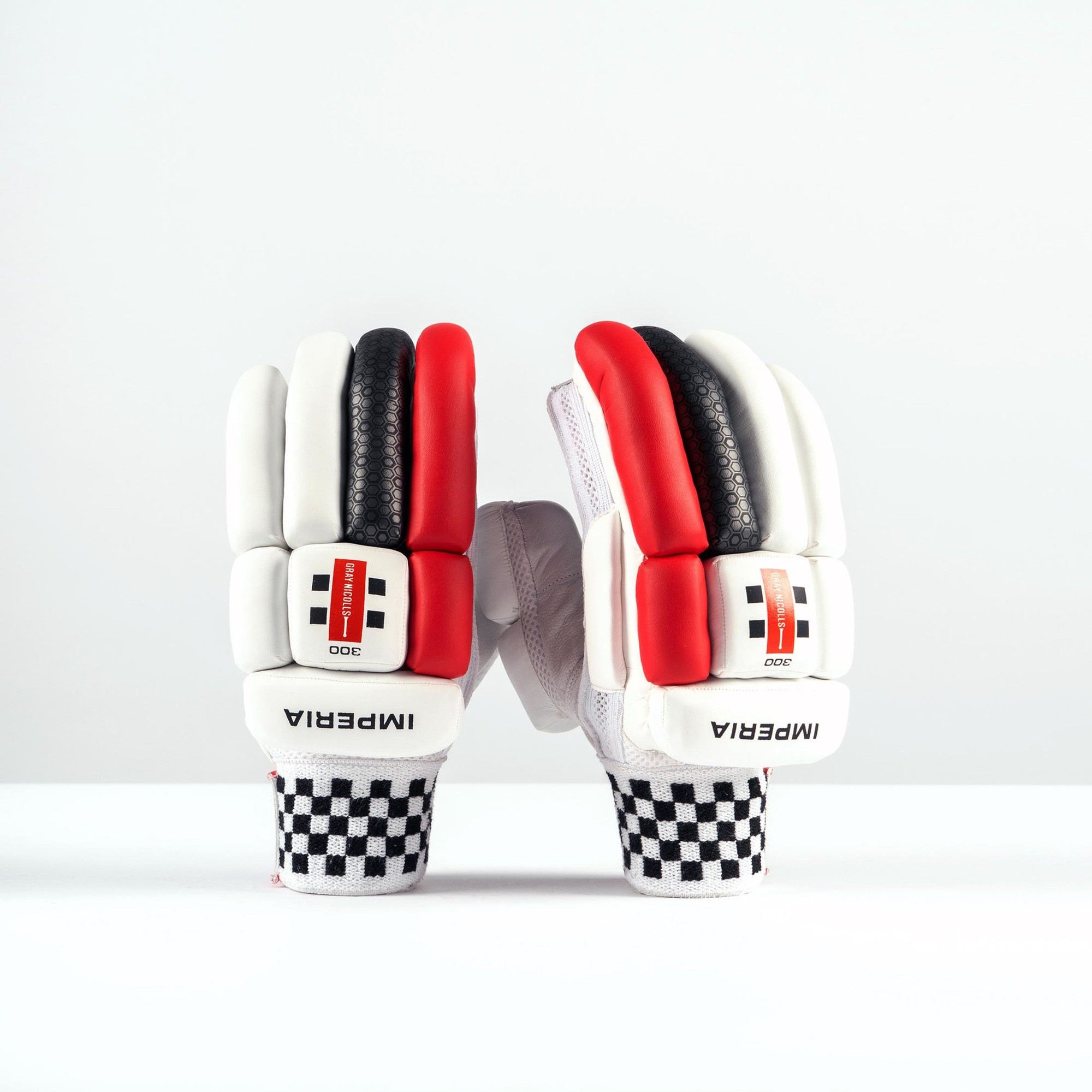 White junior batting gloves featuring red and black accents, textured grip, and a checkered pattern on the wrist, designed for enhanced protection and performance.