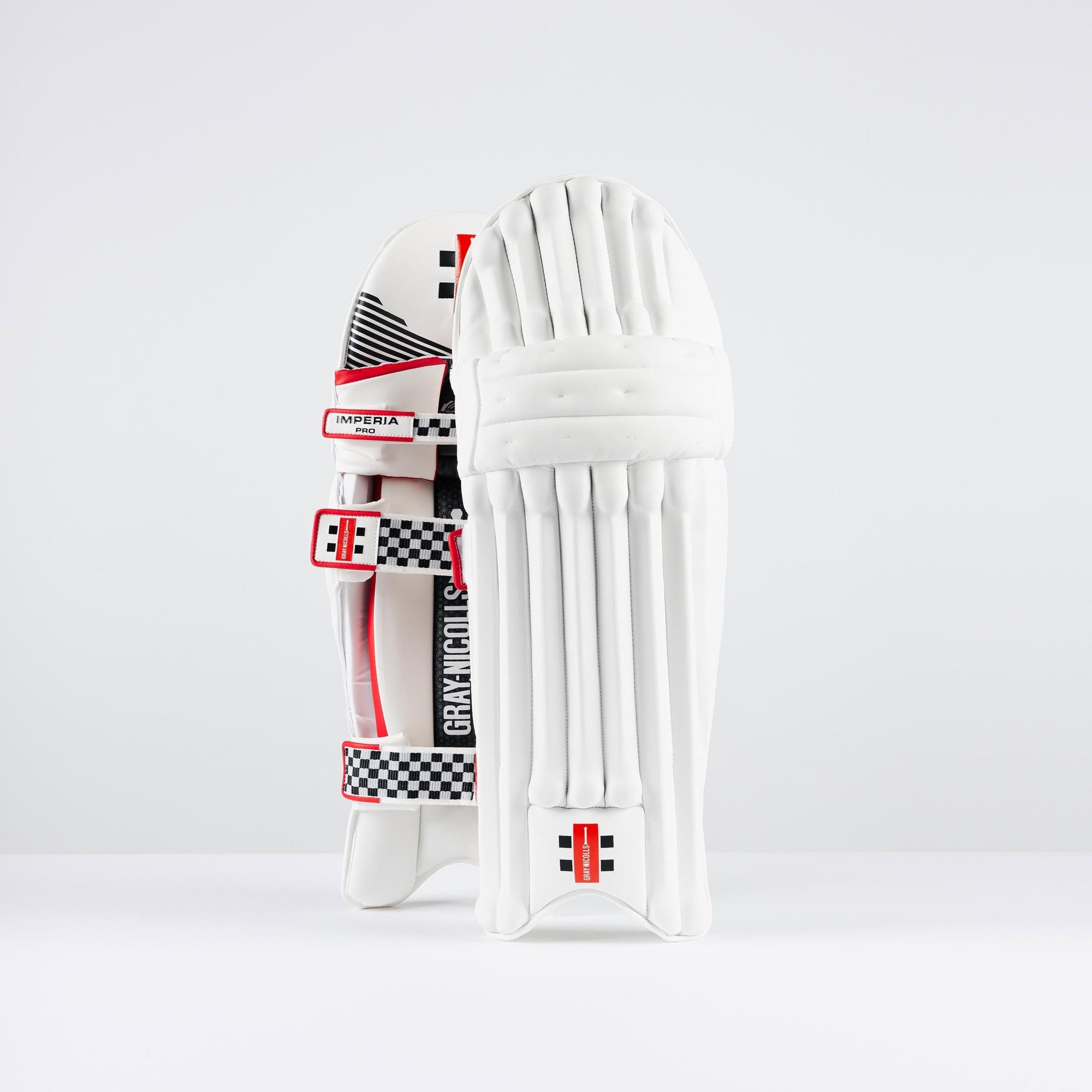 Gray-Nicolls Imperia 1.0 Pro batting pads in white with red and black accents, featuring a textured surface, adjustable straps, and a sleek design for enhanced protection.