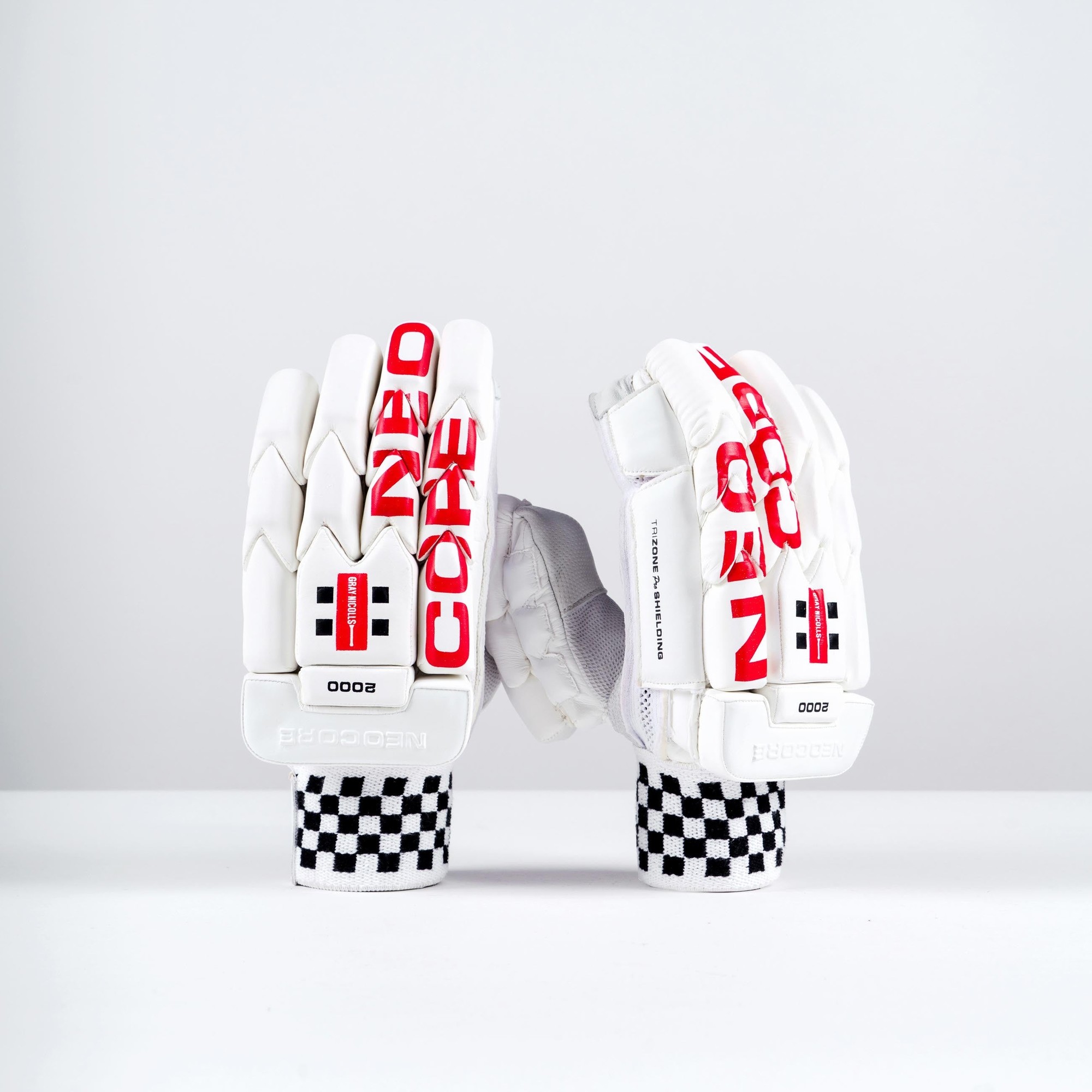 White Gray-Nicolls NEOCORE 2000 batting gloves featuring red branding, padded protection, and a checkered wrist strap for enhanced grip and comfort.