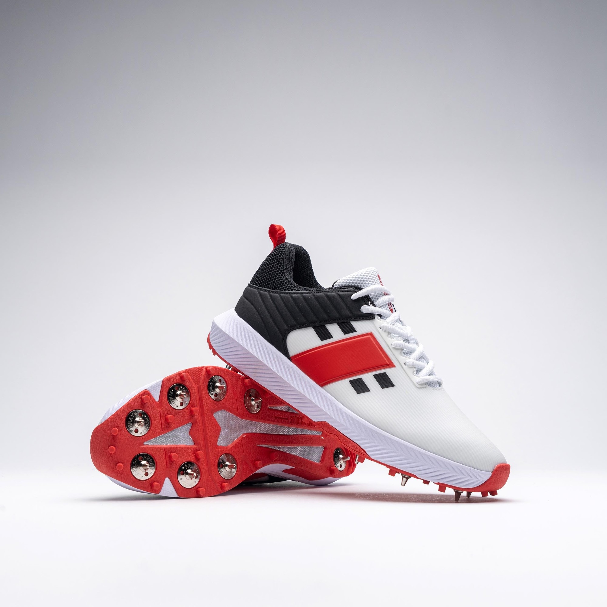 Gray-Nicolls Players 3.0 Spike Adult Shoes feature a sleek white design with black and red accents, a textured upper, and a spiked red outsole for traction.