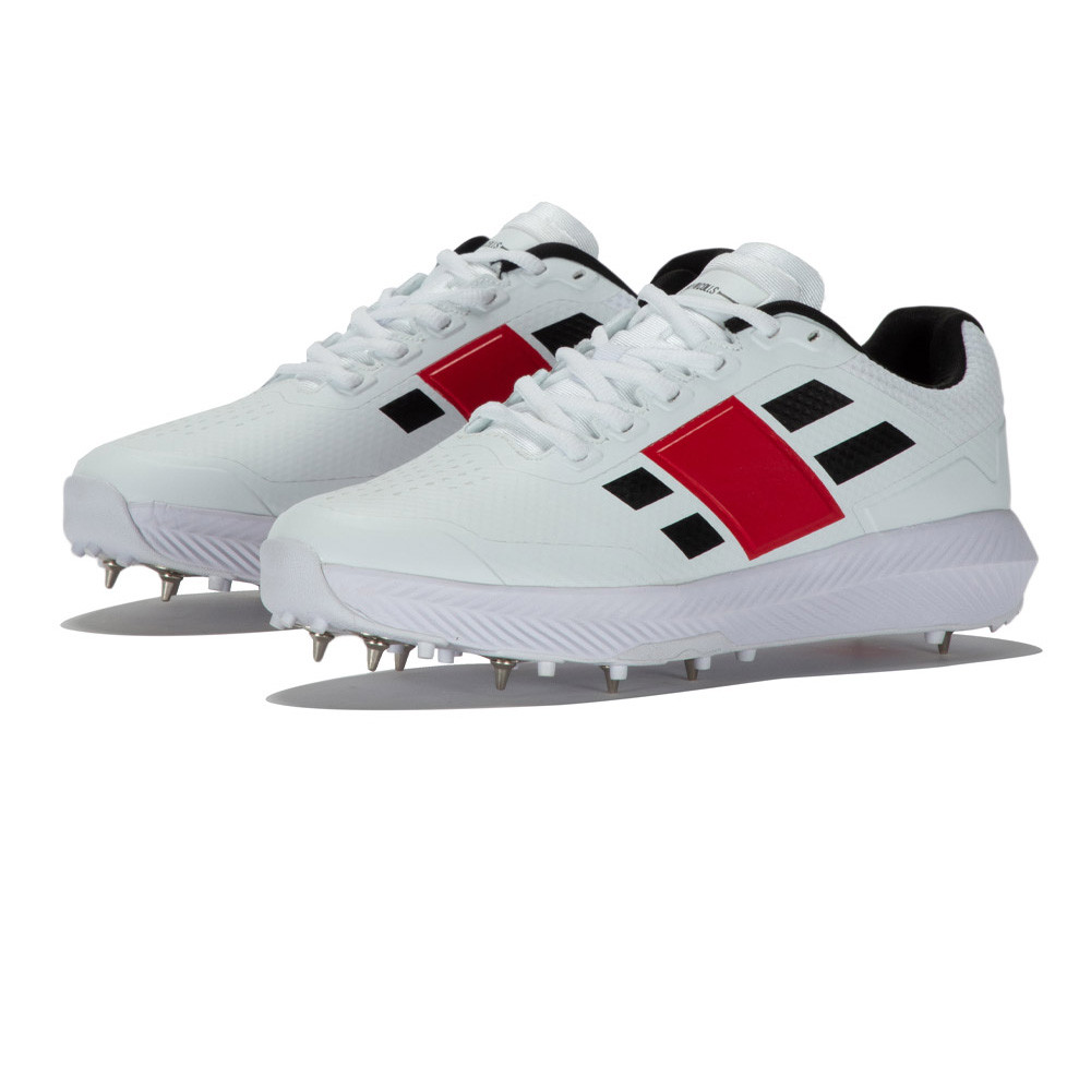 Gray-Nicolls Revo Pro 1.0 Spike shoes in white with black and red accents, featuring a textured upper, lace closure, and metal spikes for traction.