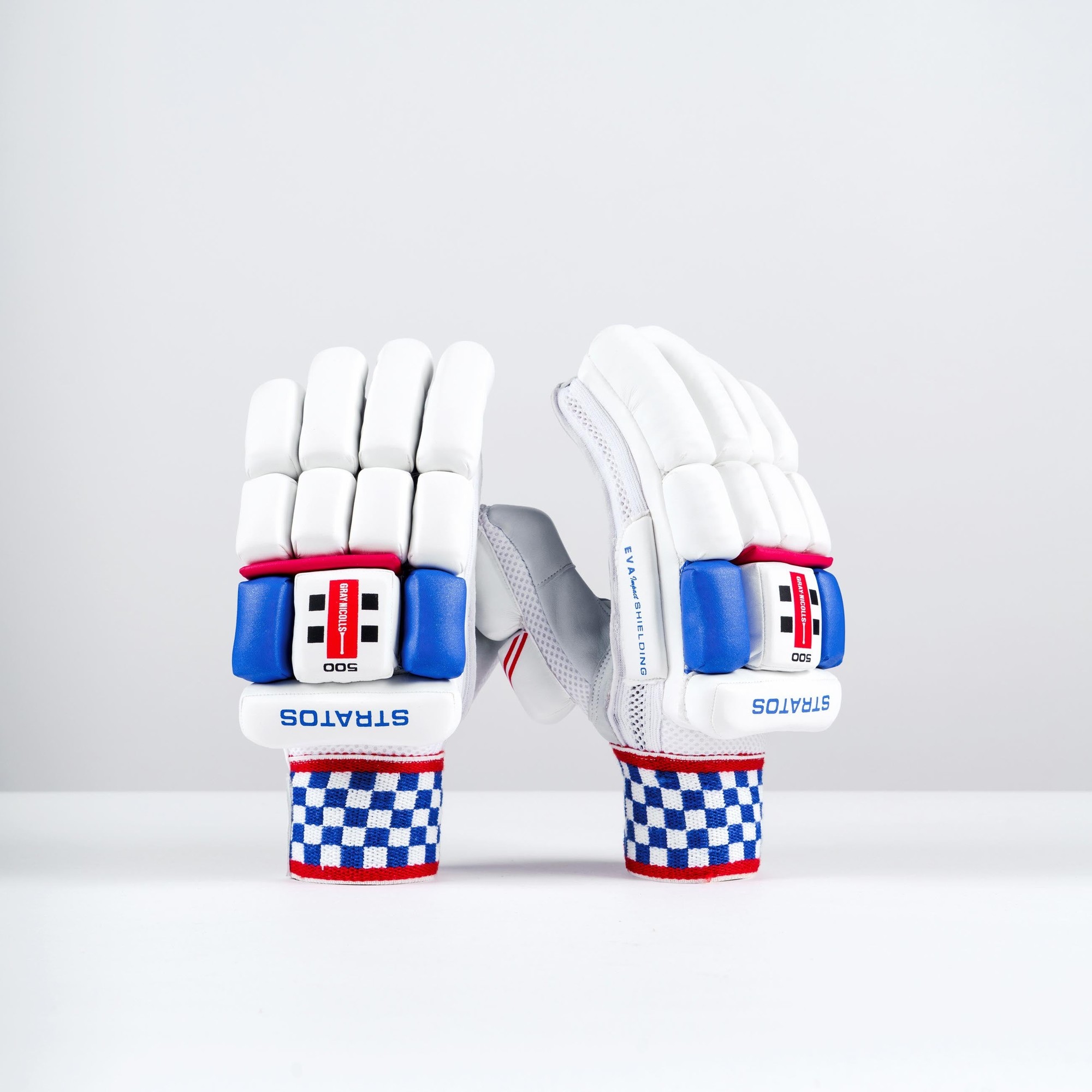 White Gray-Nicolls Stratos 1.0 500 batting gloves featuring blue and red accents, padded protection, and a checkered wrist strap design.