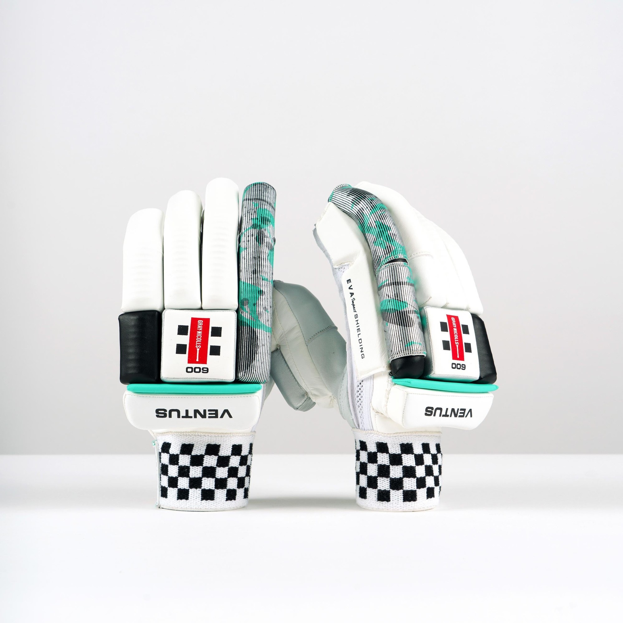 White Gray-Nicolls Ventus 1.0 600 batting gloves featuring a checkered wrist strap, padded fingers, and a green and black design on the palms for enhanced grip and protection.
