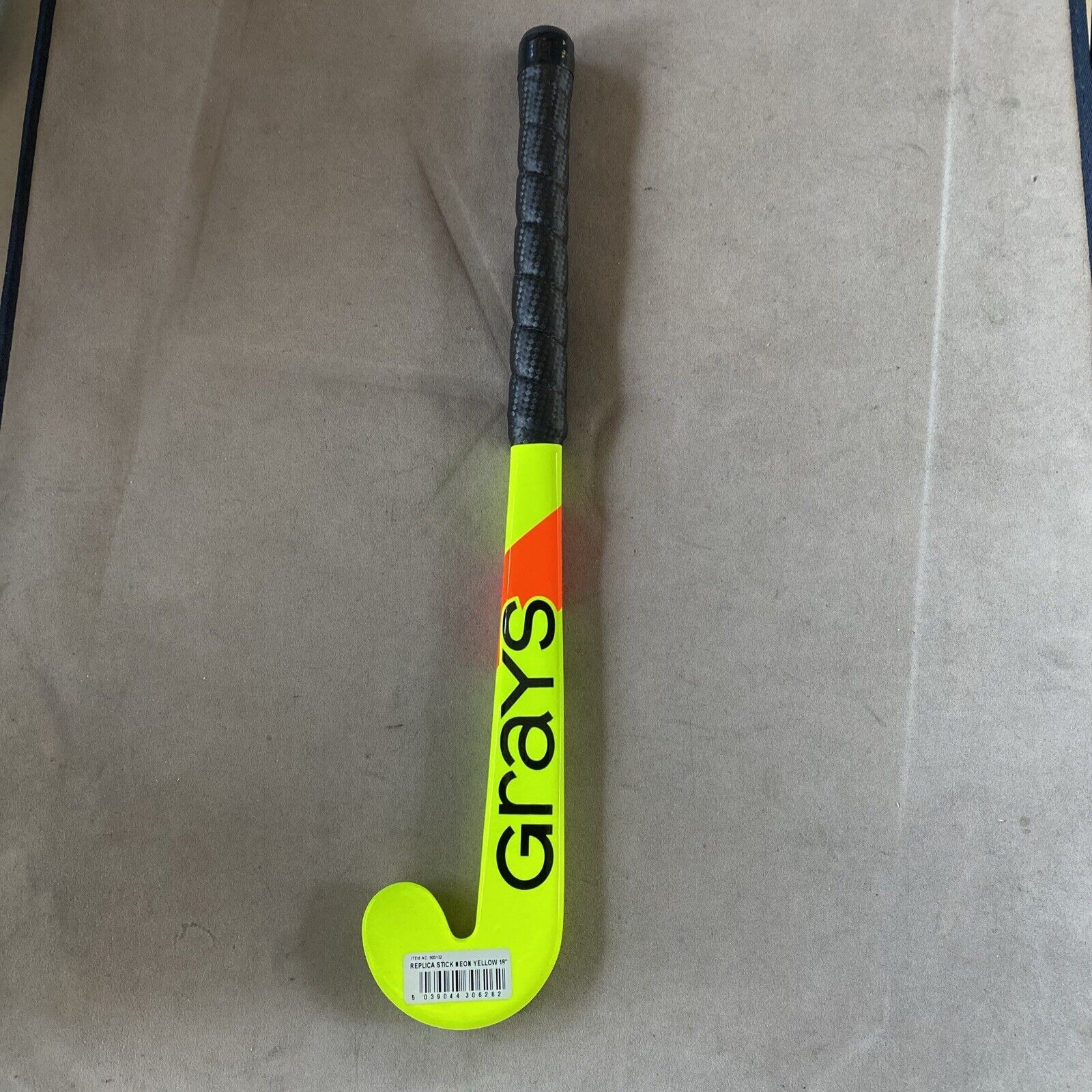 Black hockey stick with a bright yellow and orange design, featuring the "Grays" logo and a textured black grip handle for enhanced control.
