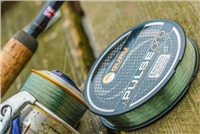 Line Guru Pulse Pro fishing line spool in dark green with a textured surface, alongside a fishing reel, set against a wooden background.