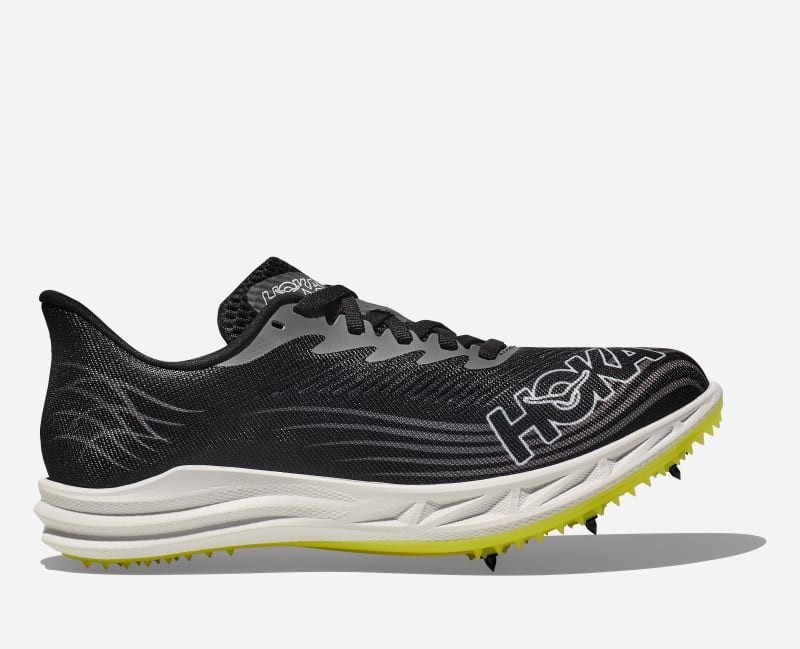 HOKA Crescendo MD 2 shoes in black and white with a lightweight mesh upper, featuring a distinctive logo, cushioned sole, and yellow spikes for traction, size 6.5 M/8 W.