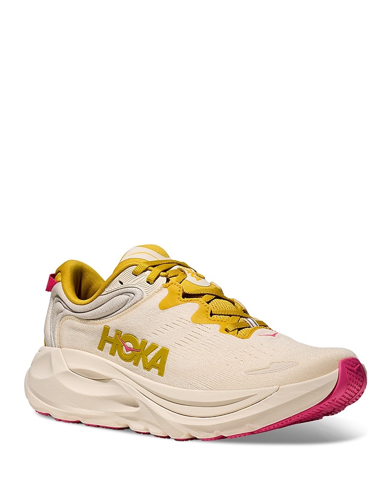 HOKA Women's Gaviota 6 Shoes feature a light birch upper with yellow gold accents, cushioned sole, and a pink outsole, designed for comfort and support.