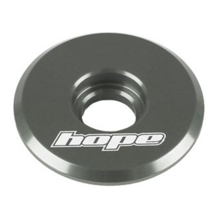 Round, smoke-colored top cap made of aluminum, featuring a central hole and engraved "hope" logo in white, designed for bike components.