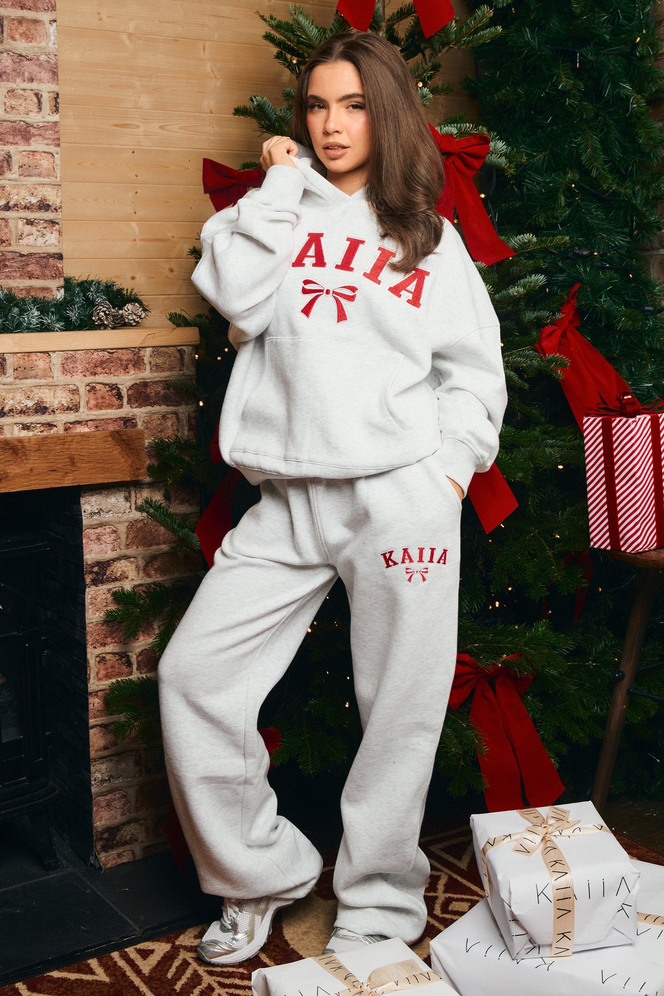 Light grey marl wide leg joggers with a ribbed waistband and red embroidered "KAIIA" logo, styled with a matching sweatshirt, set against a festive backdrop.