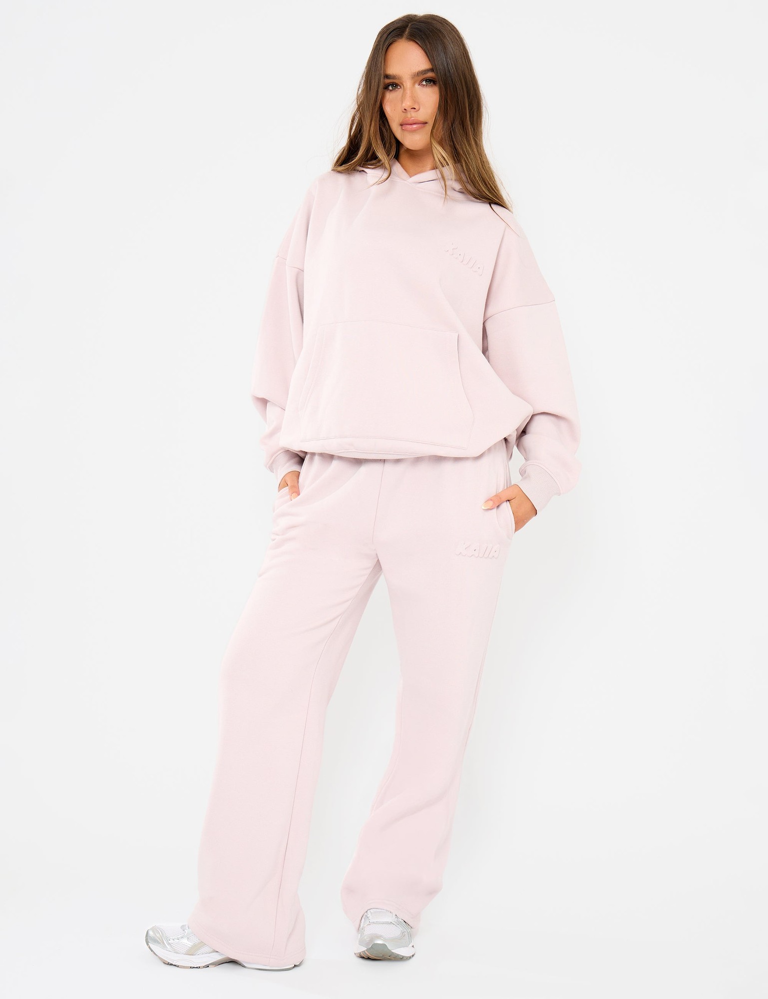 Pale dusty lilac wide leg joggers featuring an embossed logo, made from soft material, styled with an elastic waistband for comfort.