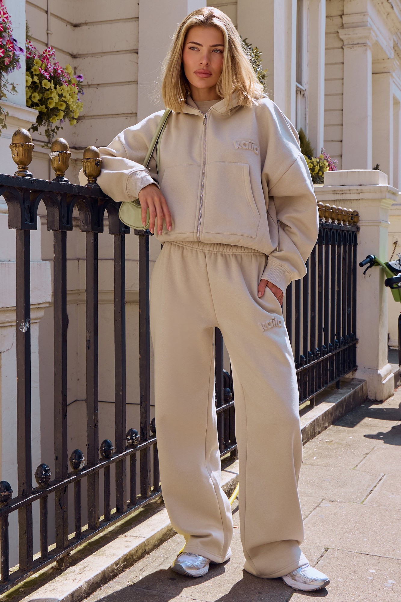 Ash taupe wide leg joggers by Kaiia, featuring an embossed texture, elastic waistband, and side pockets, styled with a matching hoodie and white slides.
