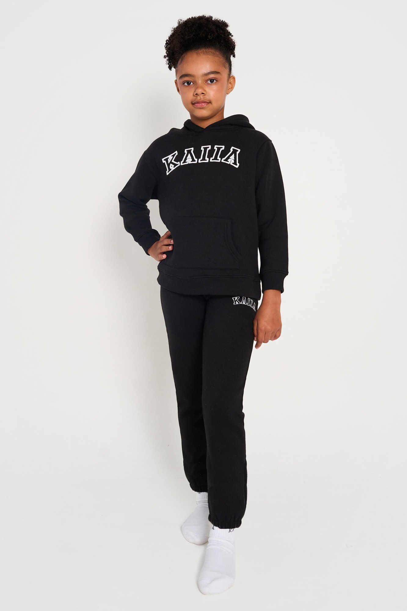 Black cuffed joggers with white "Kaiia" logo on the thigh, made from soft material, paired with a matching black hoodie featuring the same logo.