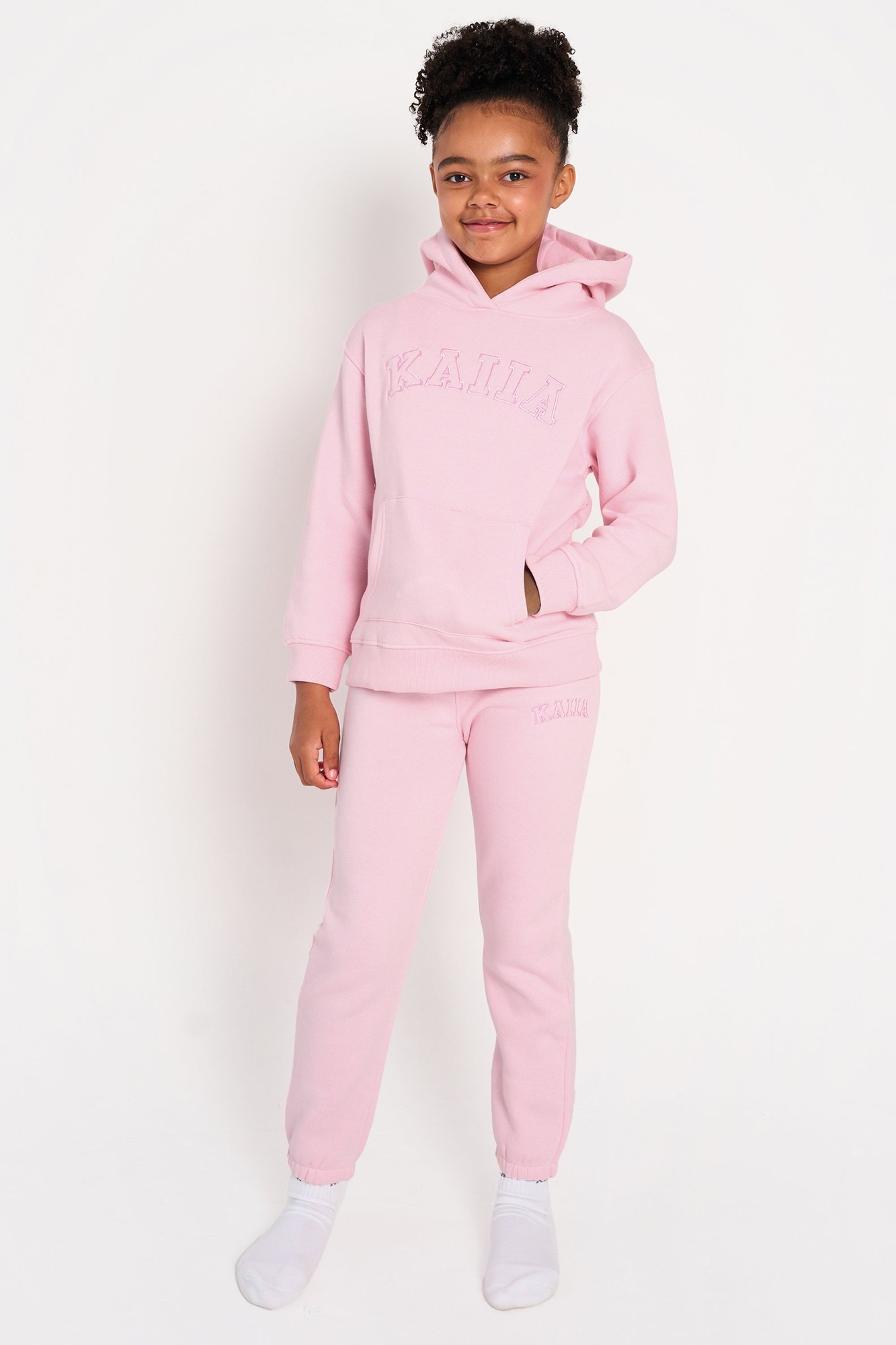 Soft pink cuffed joggers for kids by Kaiia, featuring an elastic waistband and ribbed cuffs, paired with a matching hoodie with "KAIIA" embossed on the front.