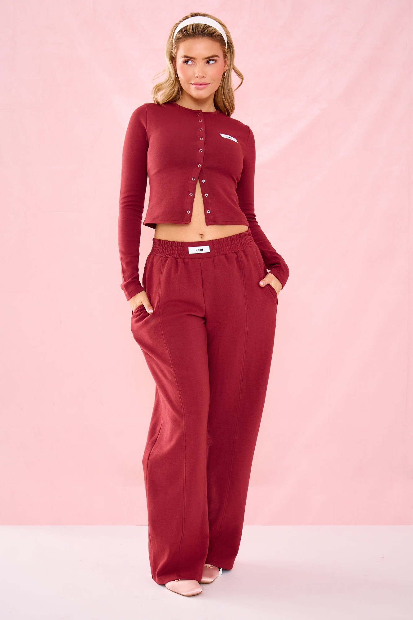 Warm berry wide-leg joggers with interlock seam detailing, featuring an elastic waistband and side pockets, paired with a matching long-sleeve top.