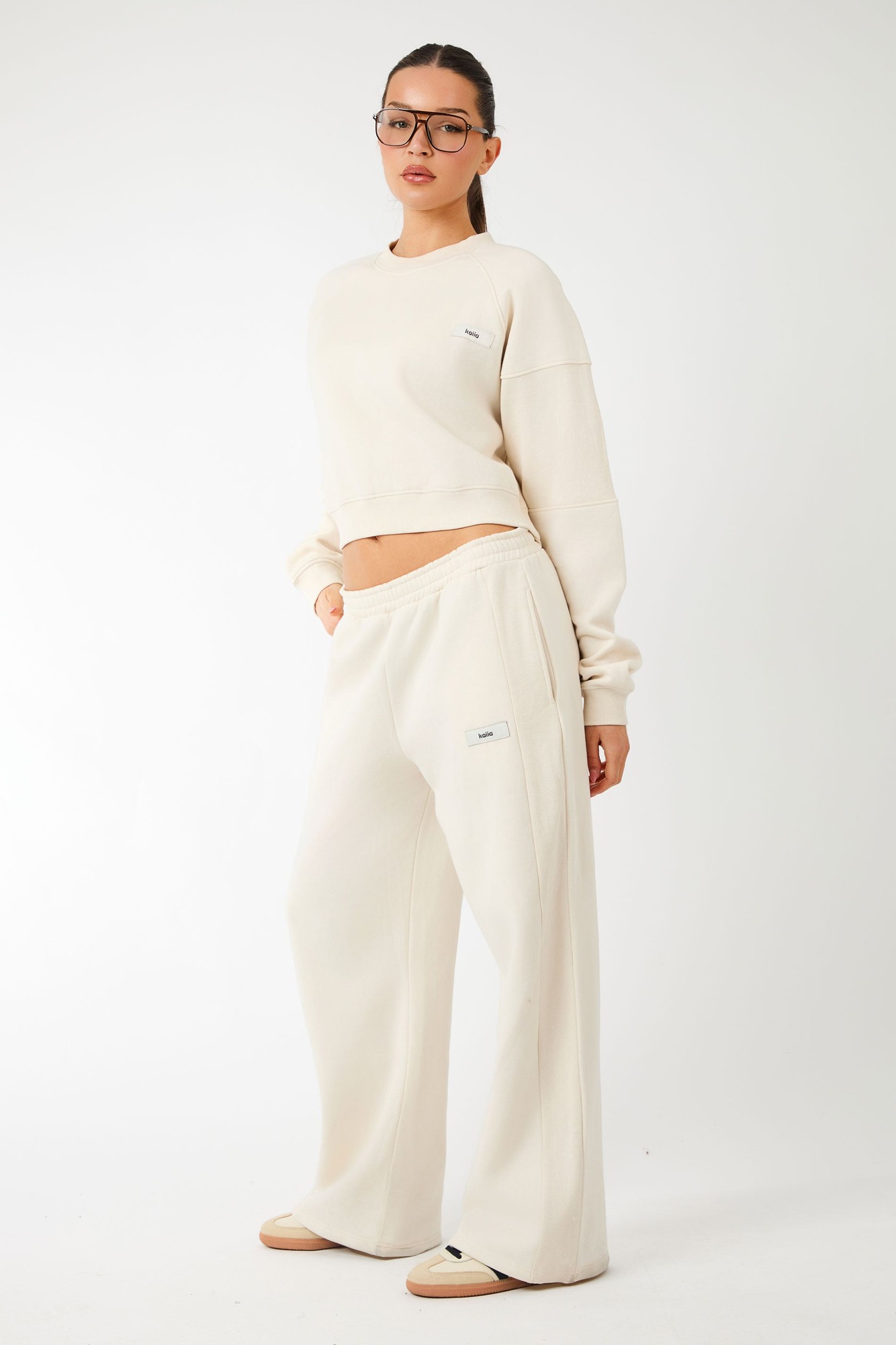 Cream ribbed wide-leg joggers featuring a comfortable elastic waistband and subtle logo detail, paired with a matching cropped sweatshirt.