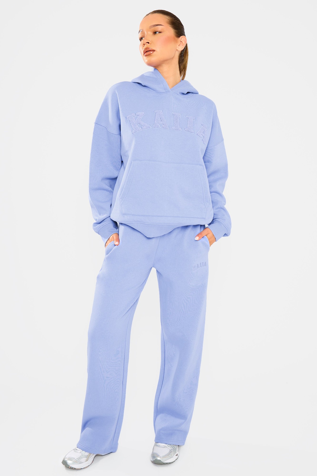 Cornflower blue wide leg joggers made from soft material, featuring an elastic waistband, side pockets, and subtle branding on the leg, styled with a matching hoodie.