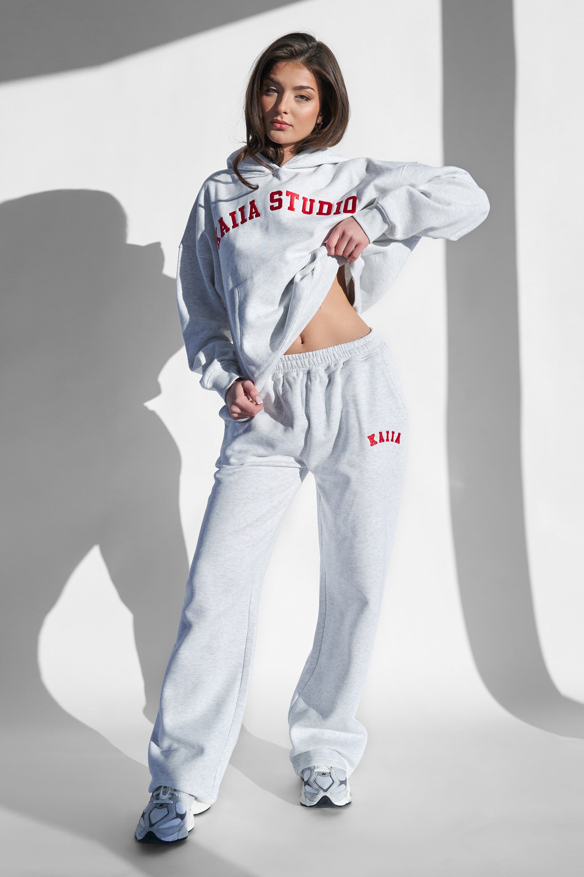 Light grey marl wide leg joggers featuring a red "Kaiia" logo on the left hip, crafted from soft material for comfort, styled with a matching hoodie.