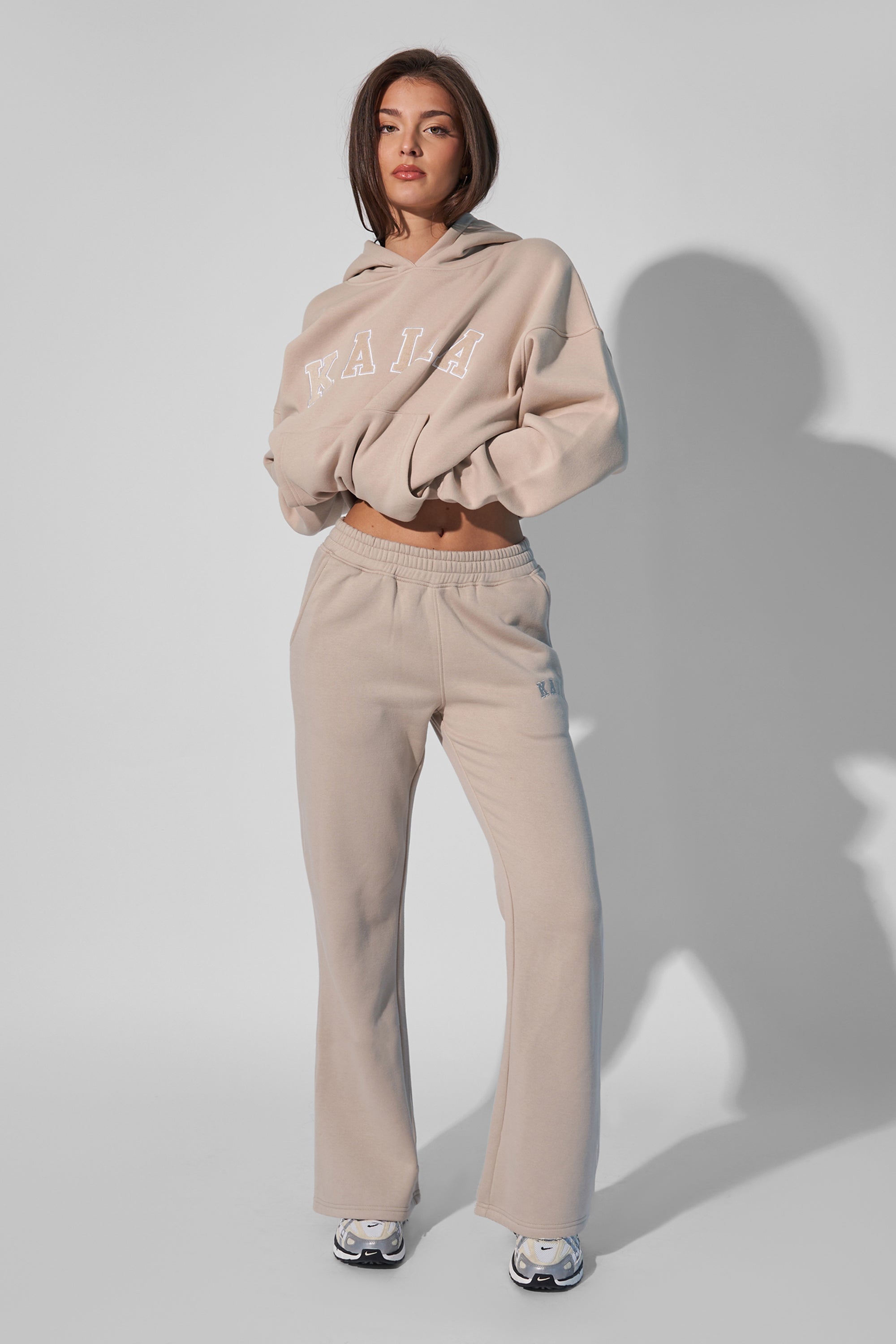 Wide leg sweat pants in a light stone color, made of soft material, featuring an elastic waistband and a subtle logo detail on the hip.