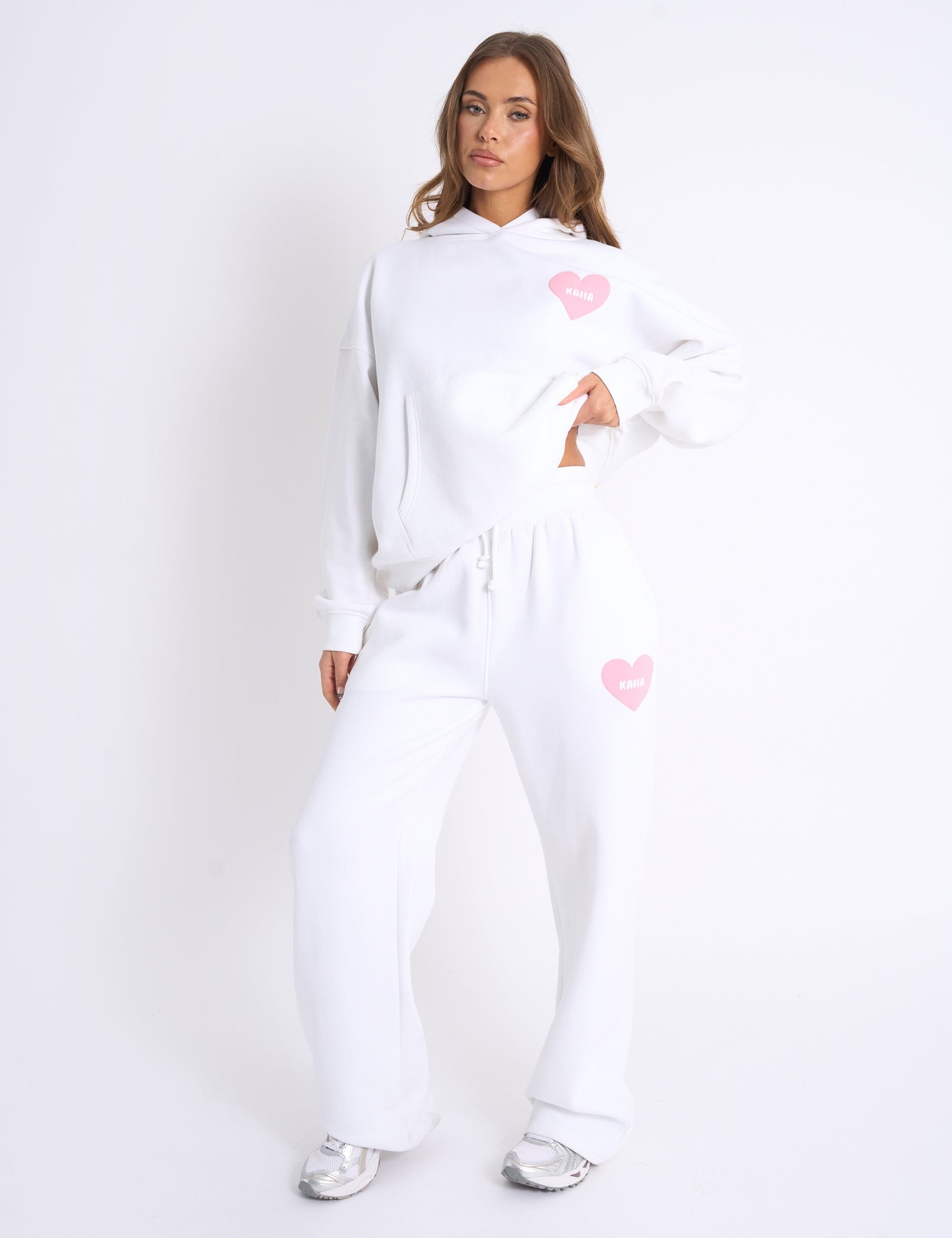 White joggers featuring a ribbed waistband and a pink heart graphic, made from soft material, styled with a relaxed fit for comfort.
