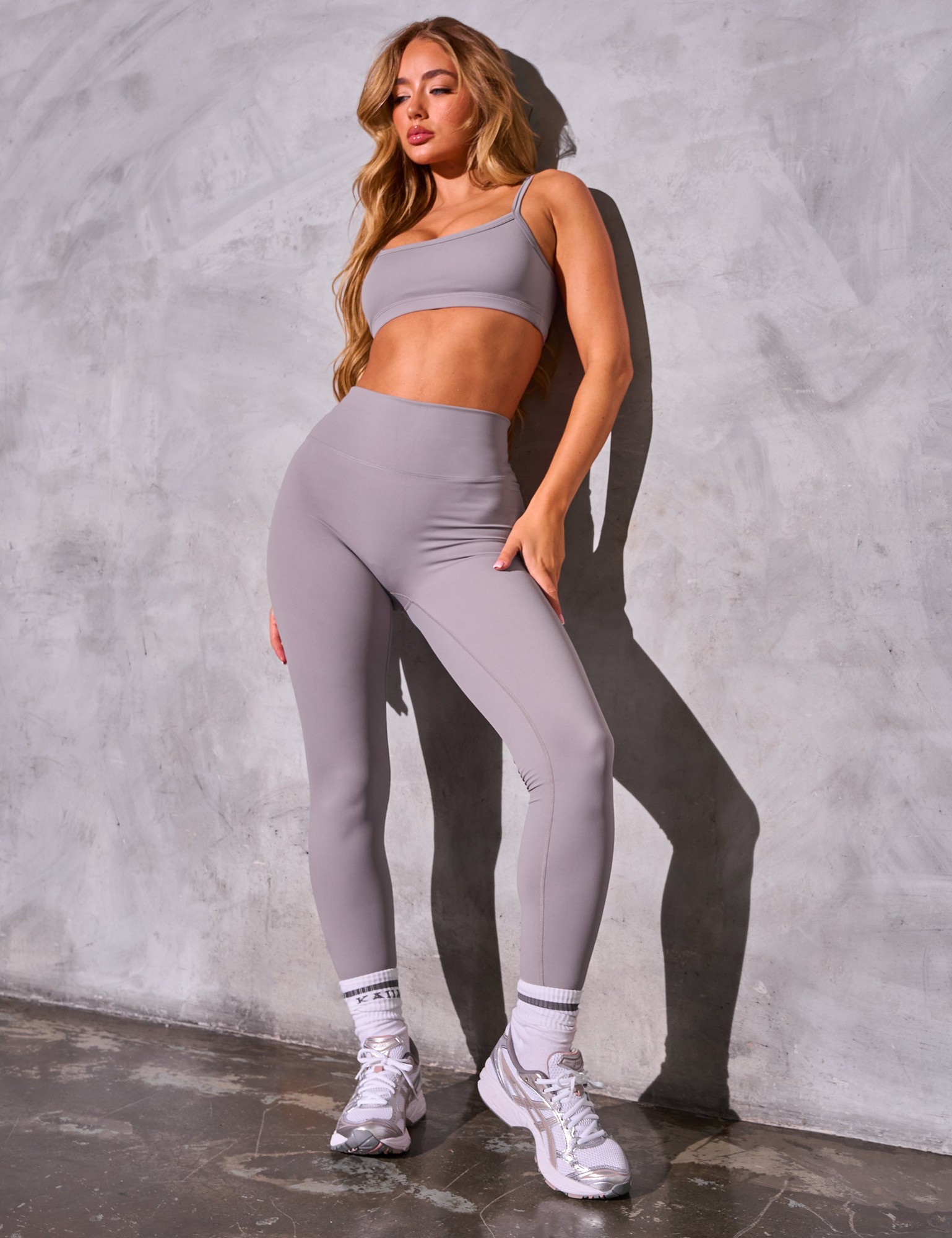 Mauve sculpt leggings made from stretchy material, featuring a high waistband and a sleek, form-fitting design, paired with a matching crop top and white sneakers.