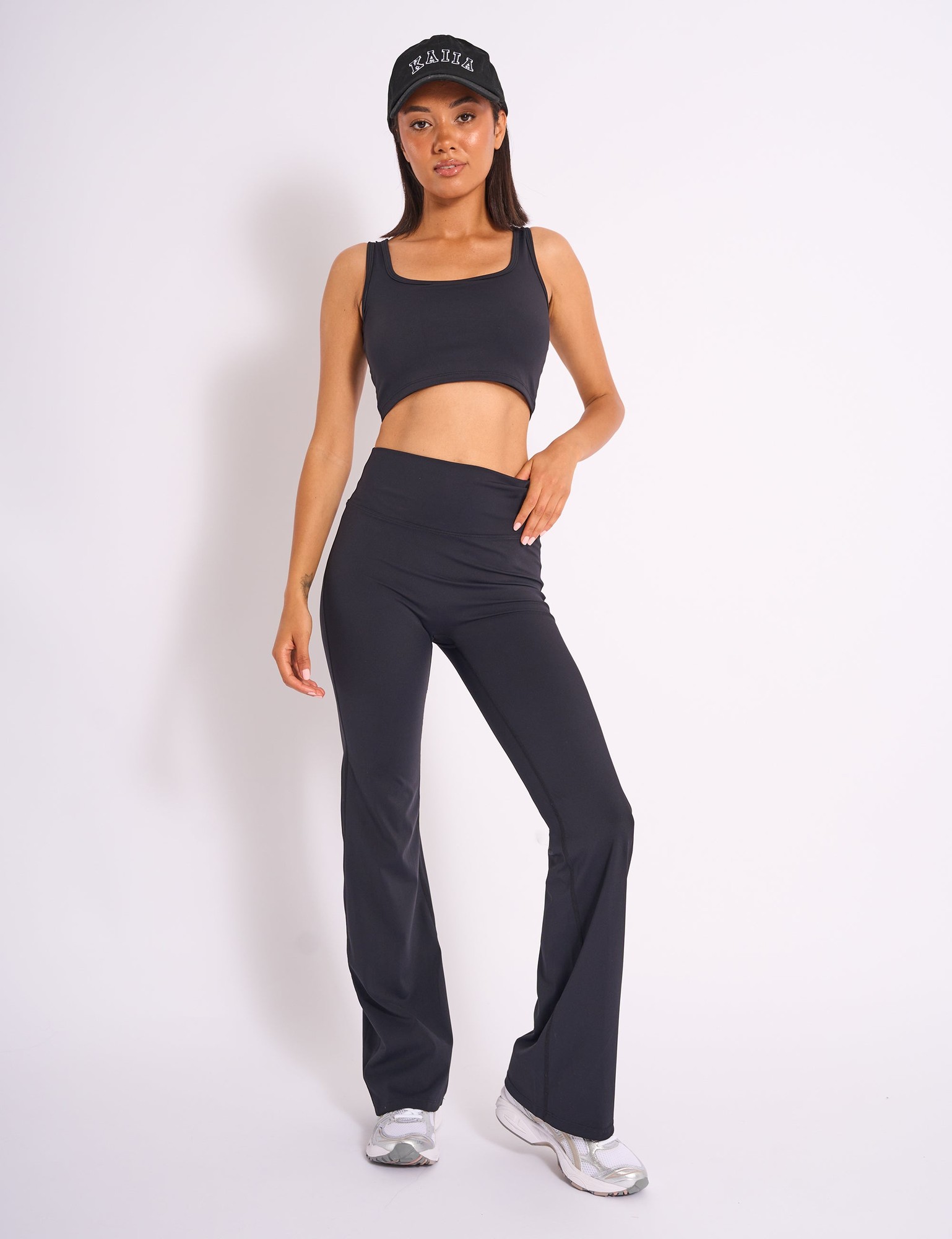 Black sculpt yoga pants with a high waistband, paired with a matching black crop top and a black cap, featuring a sleek, stretchy material ideal for workouts.