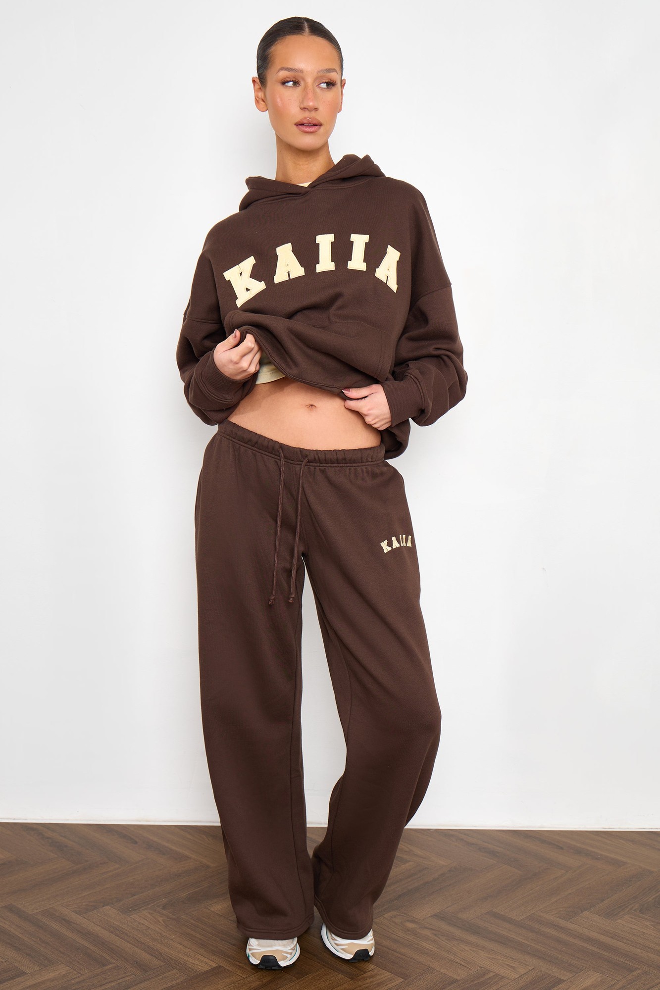 Wide leg joggers in bitter chocolate with butter yellow "KAIIA" slogan, featuring a comfortable fit and soft material, paired with a matching hoodie.
