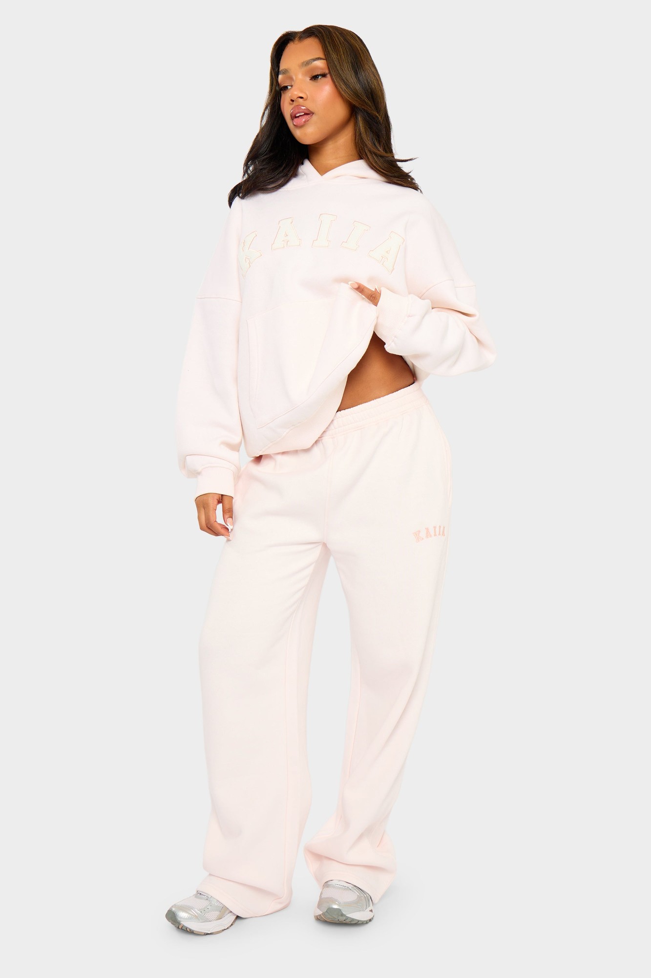 Shell pink wide leg joggers made from soft material, featuring an elastic waistband and subtle branding on the side, styled with a matching oversized hoodie.