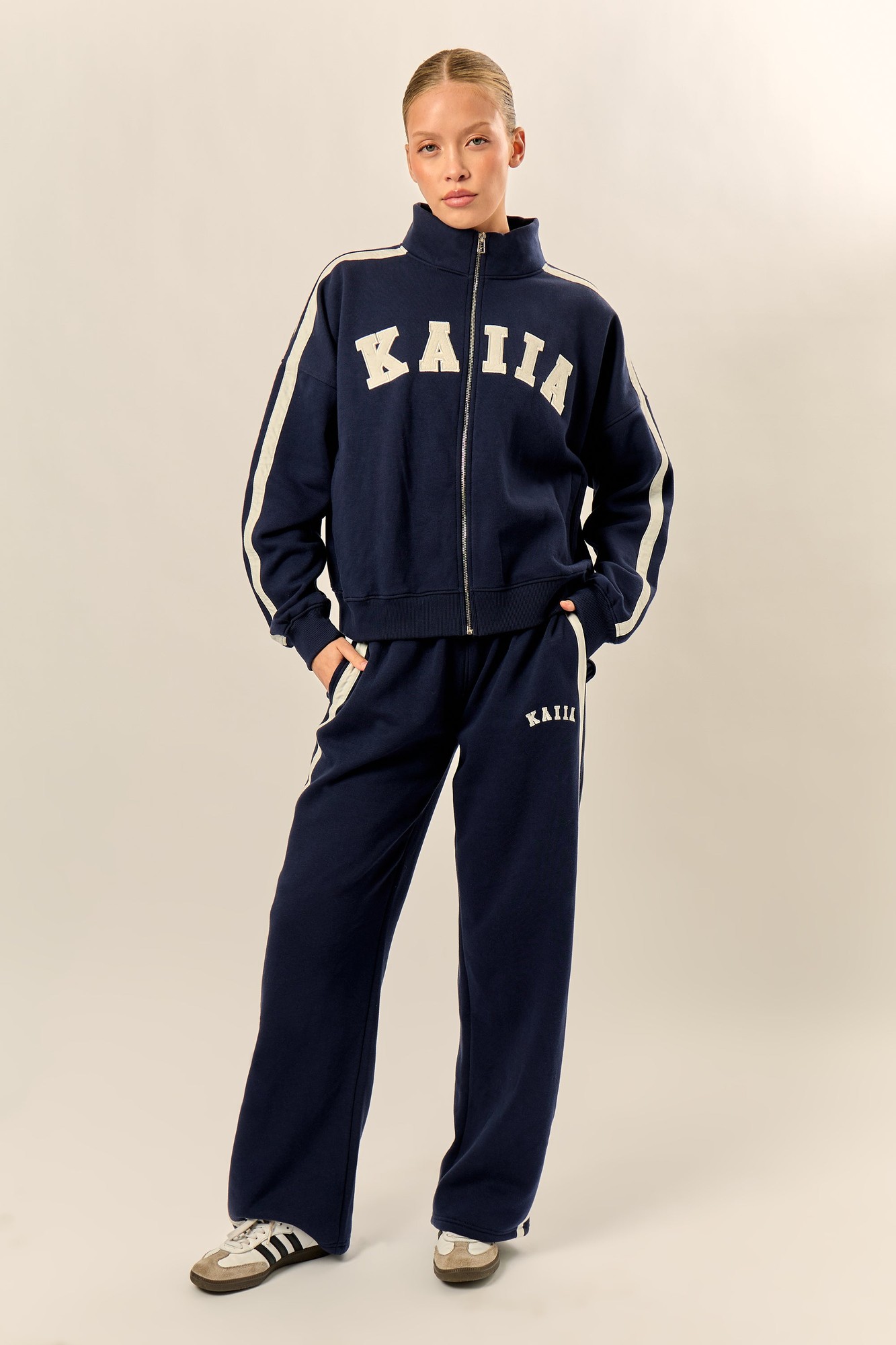Navy and cream wide-leg joggers featuring a sporty stripe design, soft fabric, and the "Kaiia" logo on the left hip, styled with a matching zip-up jacket.