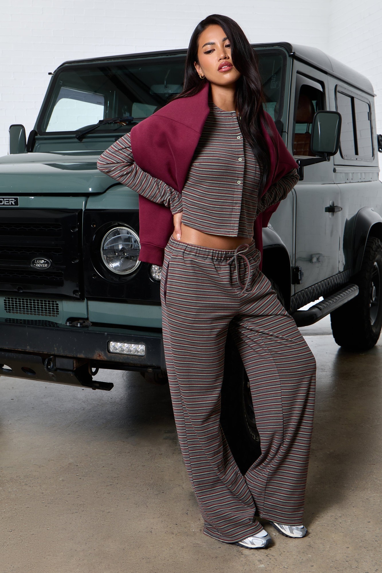 Brown multi-striped fleece wide leg trousers feature a comfortable fit with an elastic waistband, paired with a matching cropped top and a maroon cardigan.