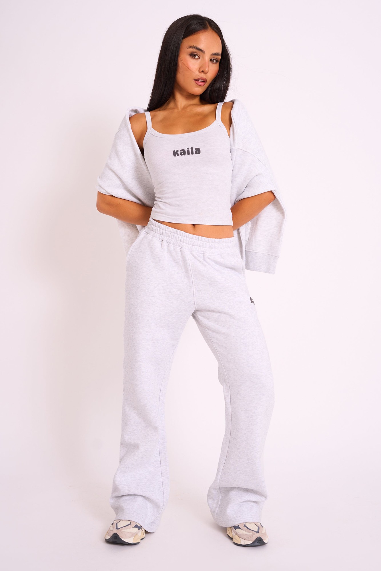 Grey marl wide leg joggers made from soft material, featuring an elastic waistband and a small black Kaiia logo on the side, styled with a matching cropped top and oversized sweater.