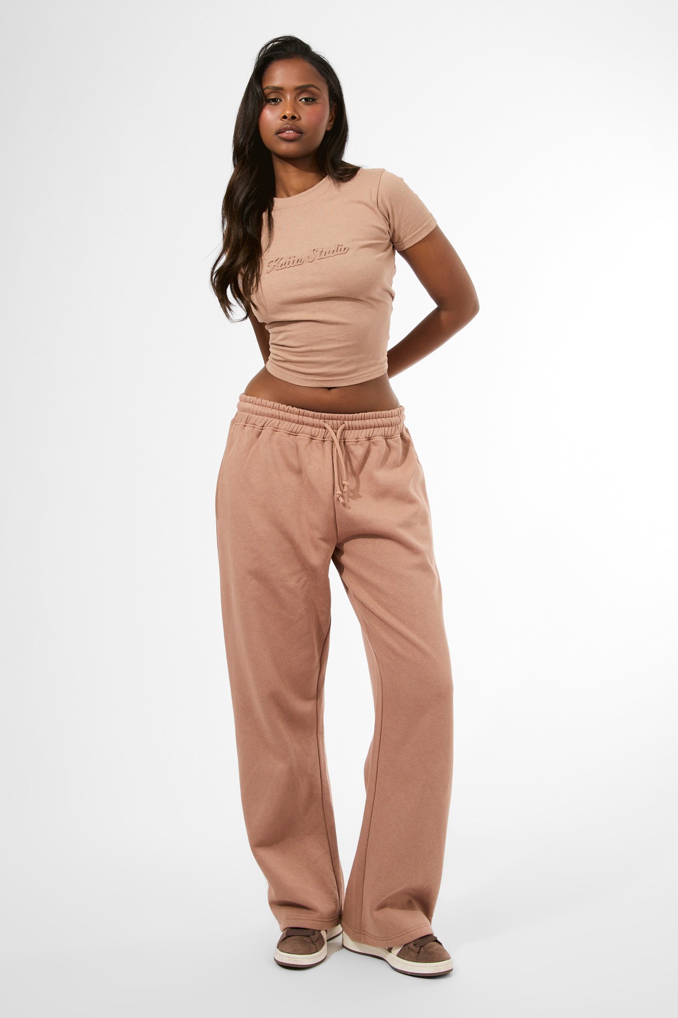Wide leg joggers in milk chocolate color, featuring an embossed script logo, made from soft material with an elastic waistband for comfort.