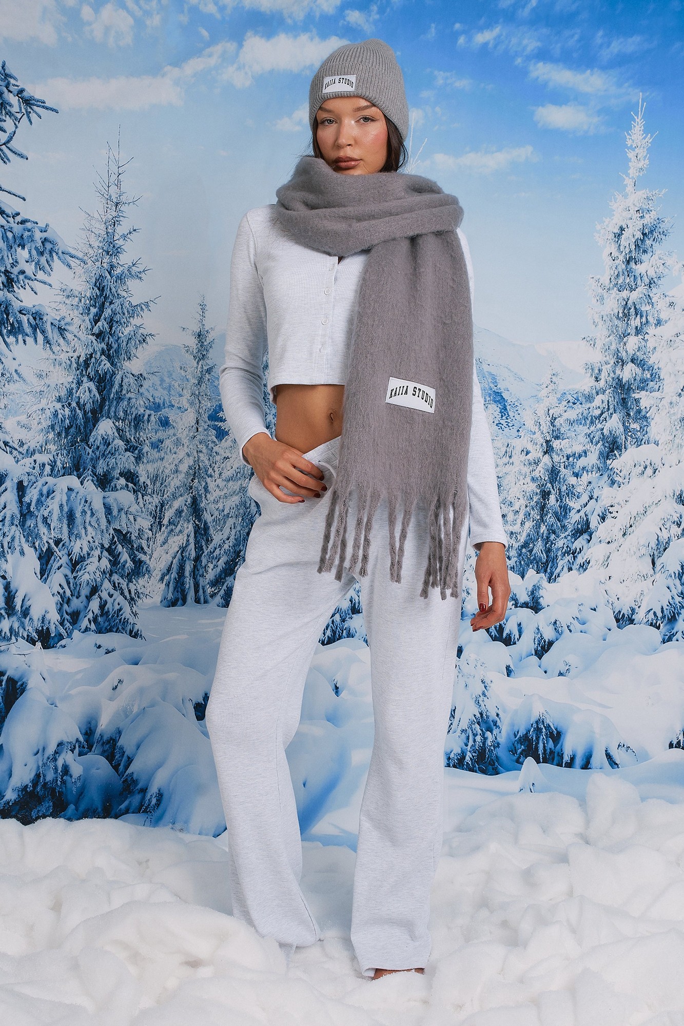 Grey melange waffle wide leg joggers made of soft material, paired with a matching grey beanie and scarf, styled against a snowy winter backdrop.