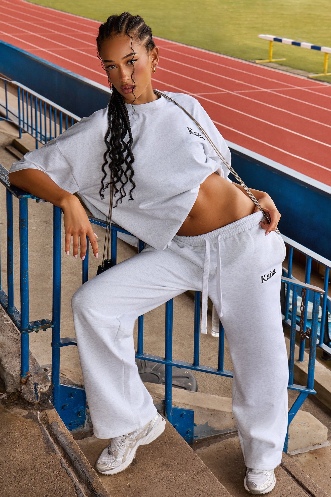 Wide leg joggers in grey marl with a black logo, paired with a matching cropped grey sweatshirt, featuring a relaxed fit and drawstring waist, styled on a model.